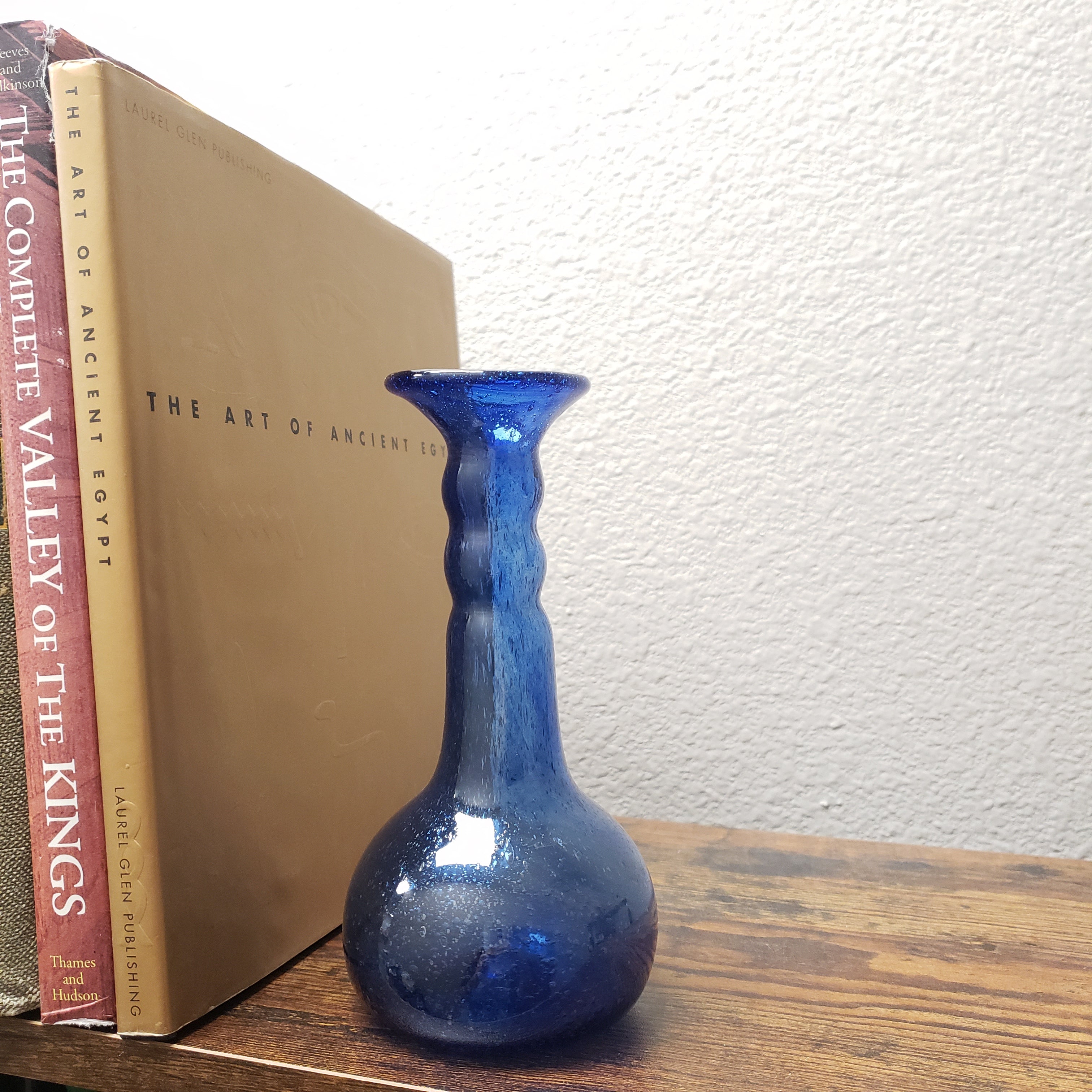 Blue glass vase on top of two books with a plain background