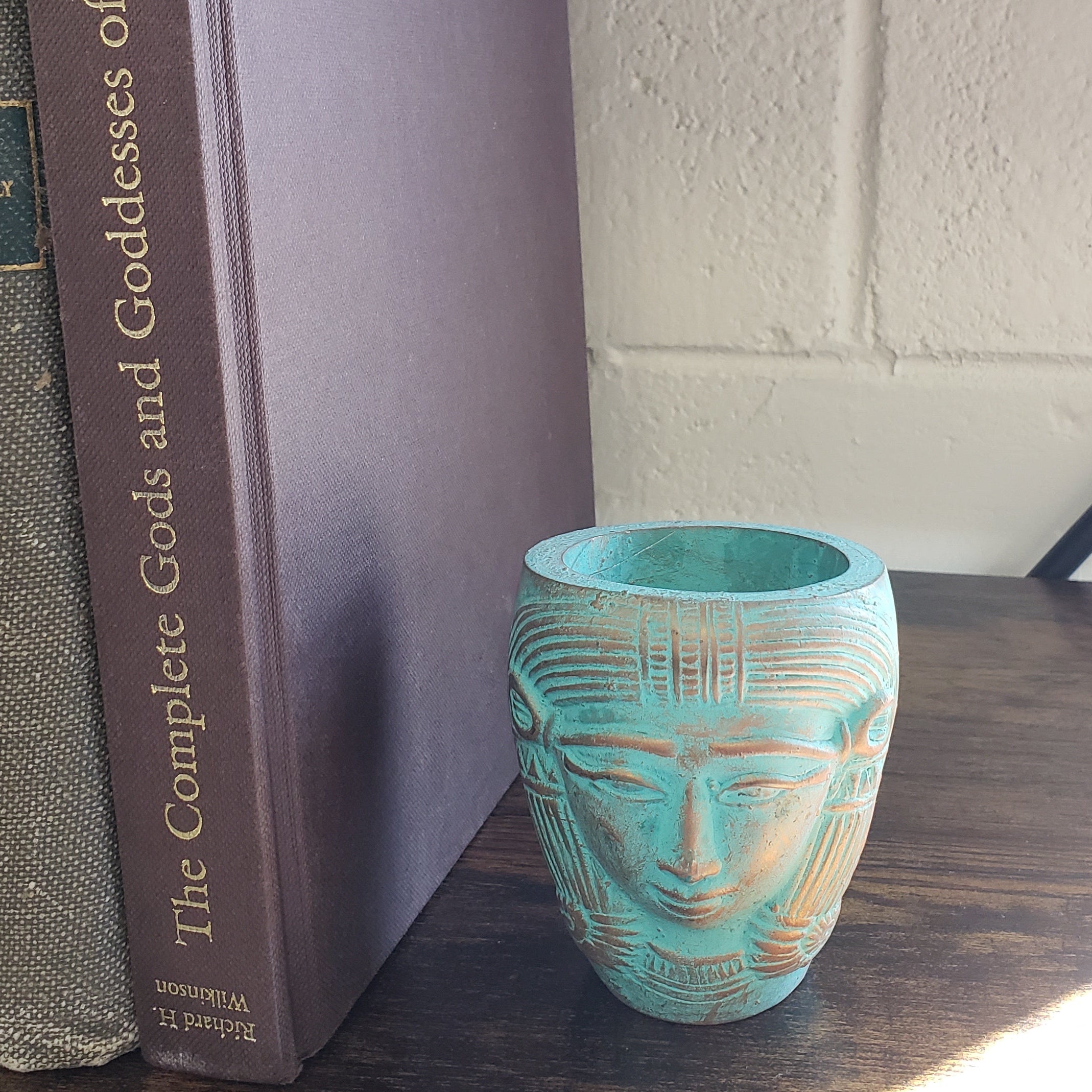 Turquoise decorative object on a stack of books with a brick wall background