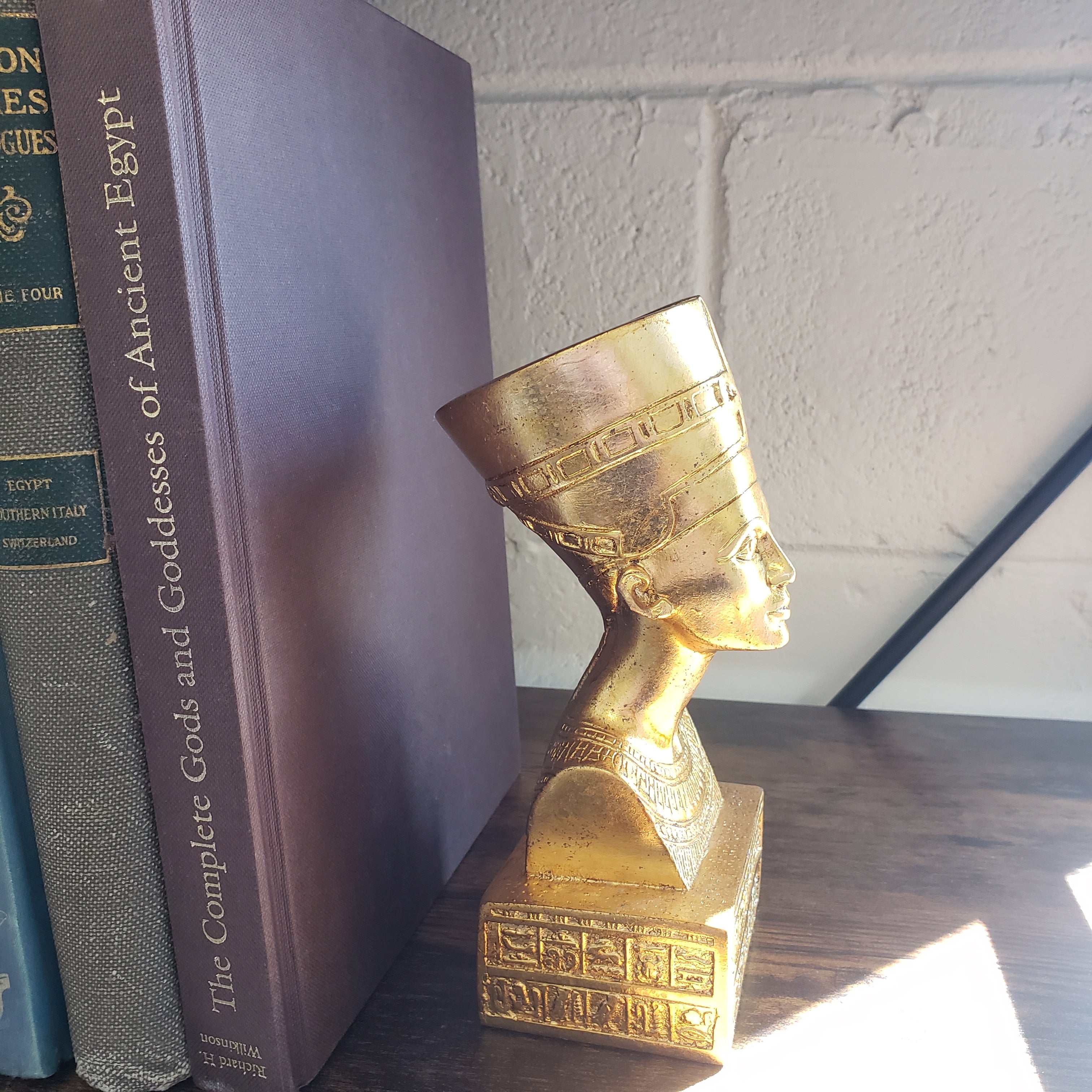 Gold bust of a pharaoh next to books on an ancient Egypt theme