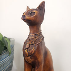 Brown sculpture of a cat with intricate designs on a white background