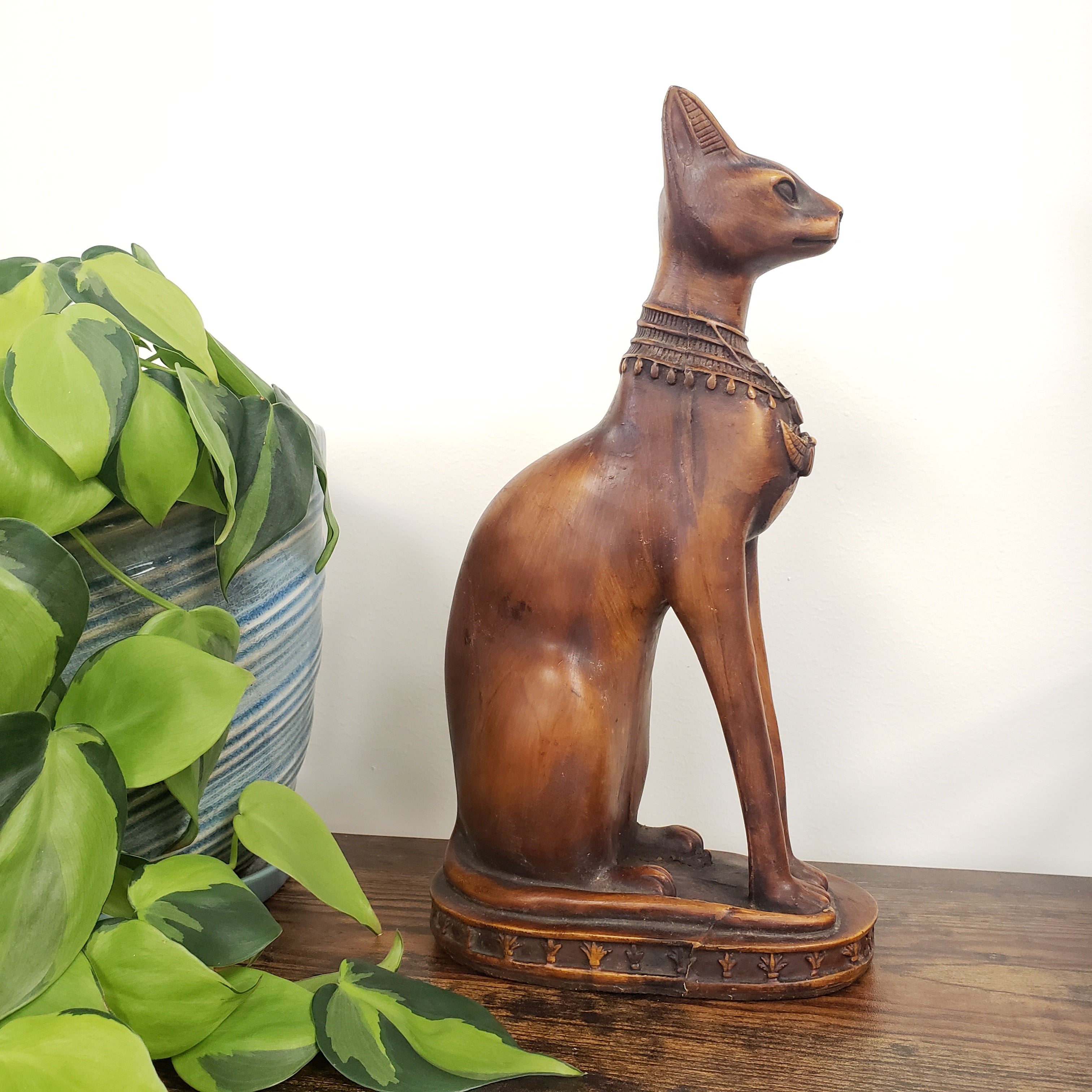 Decorative animal figure on a white wall with green plants in the foreground