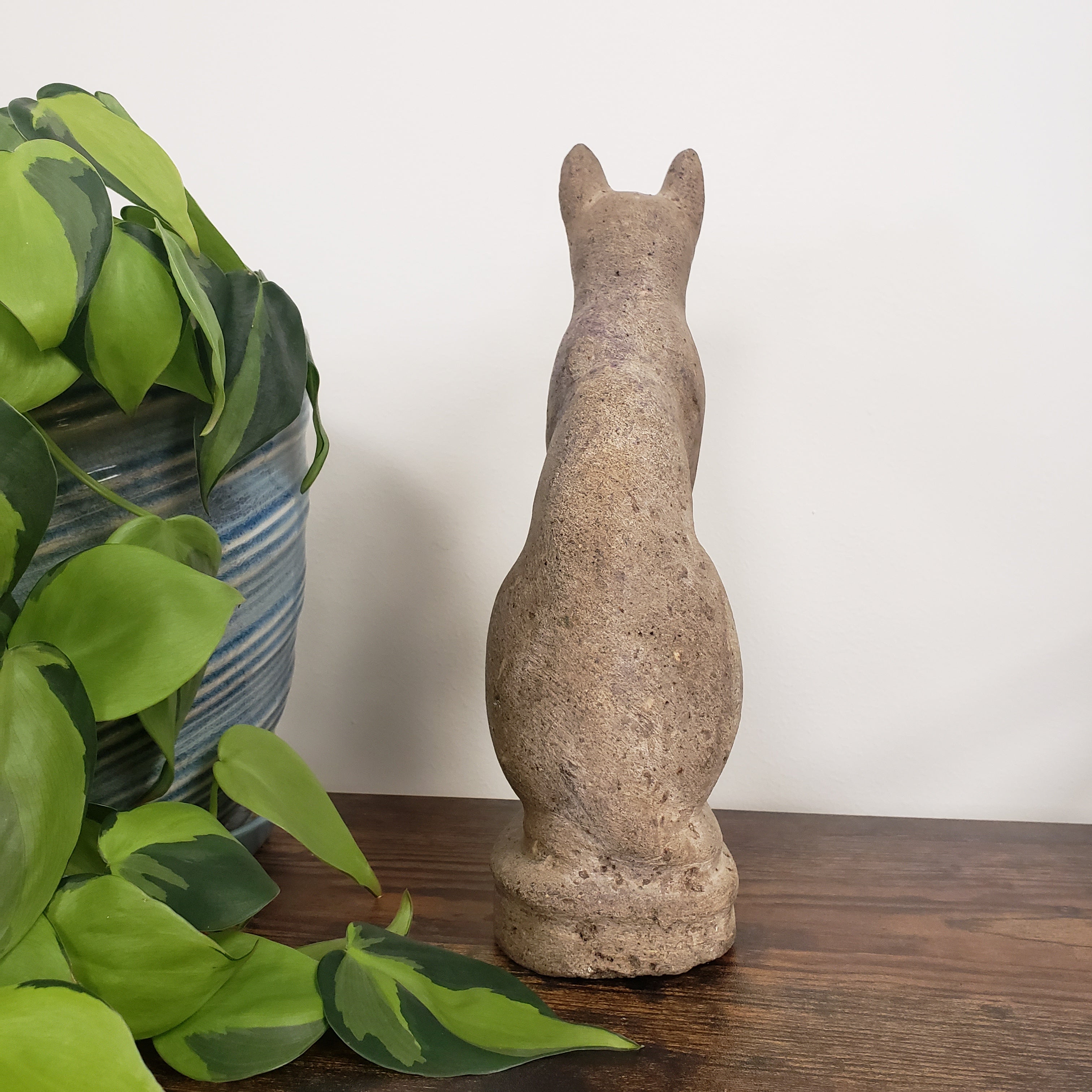 Decorative stone cat statue with greenery in the foreground