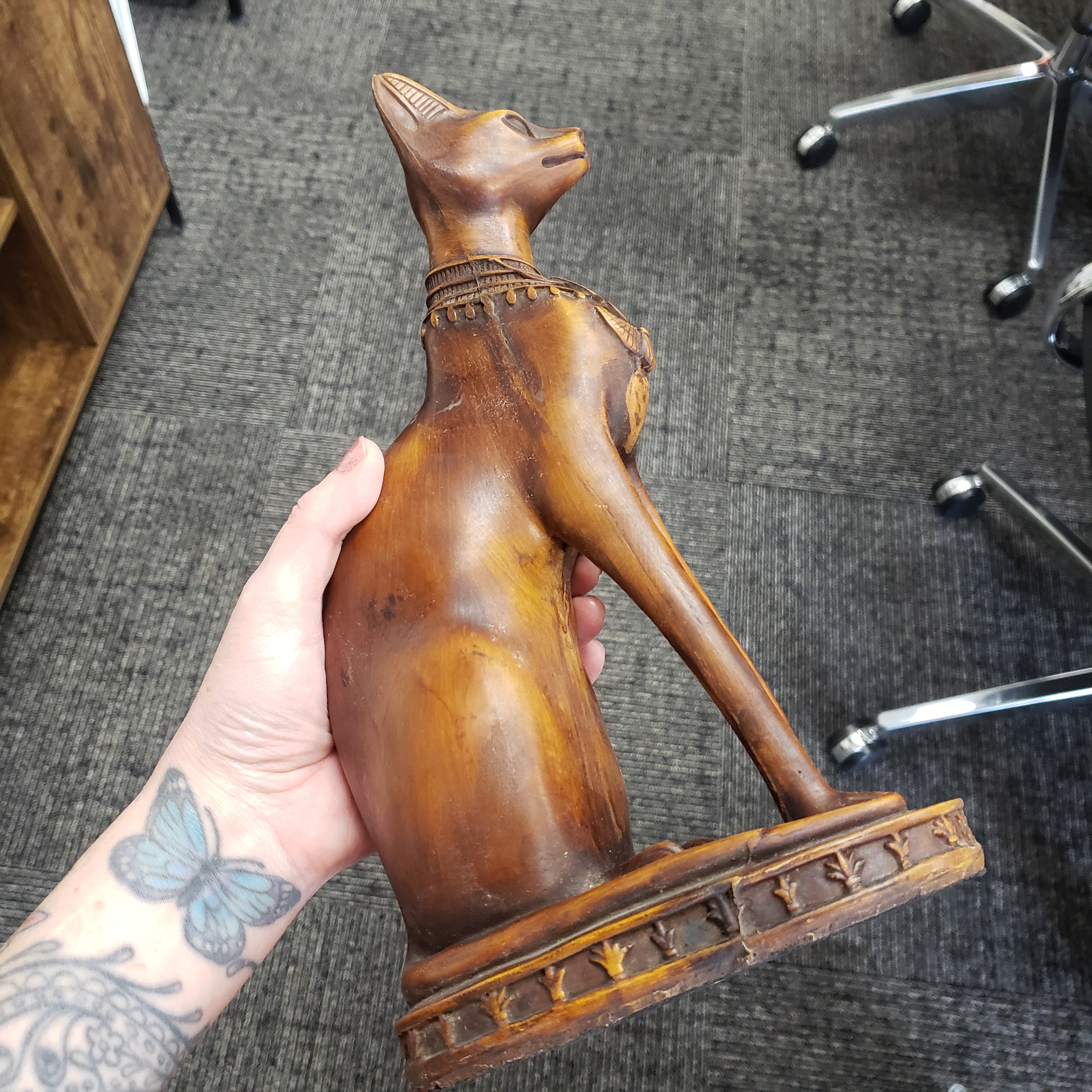 Wooden sculpture held by a hand on a textured gray surface