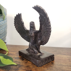 Decorative Egyptian Isis statue on a wooden surface with a white background