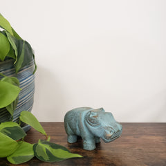 Decorative green hippo statue on a wooden door with plants in the foreground