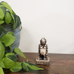 Decorative Egyptian hippo goddess statue on a wooden board with green leaves in the foreground