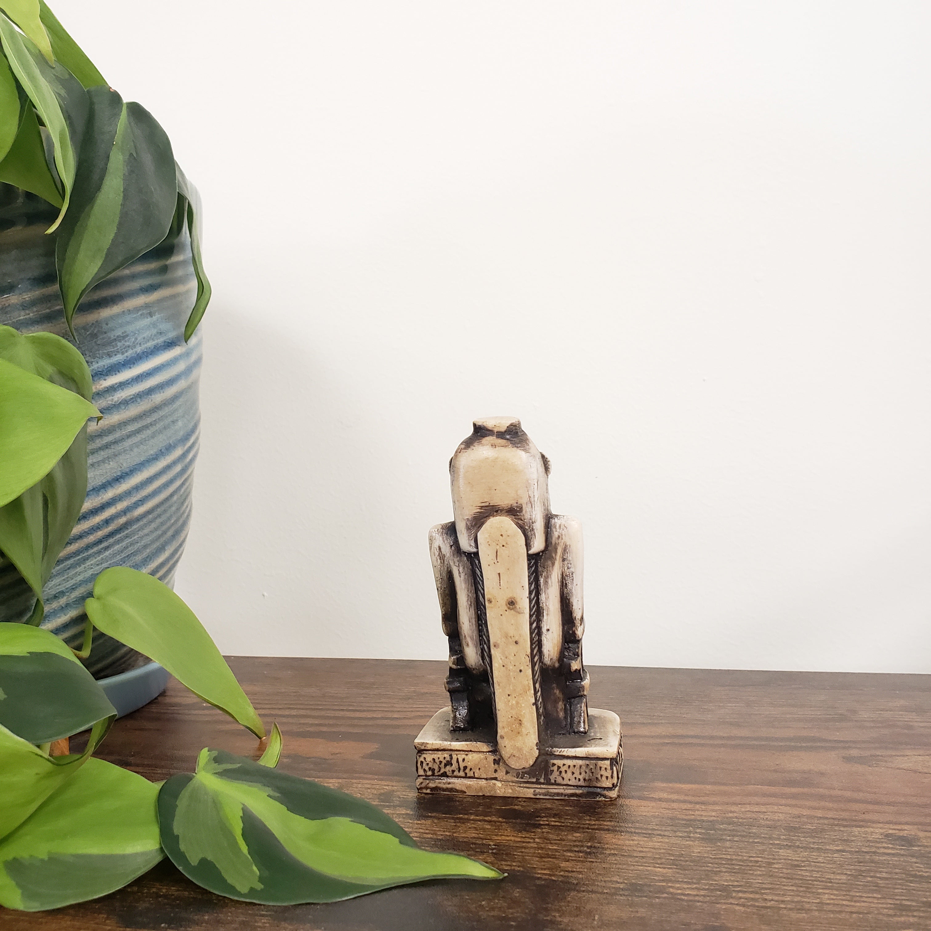 Decorative Egyptian hippo goddess on a wooden door with green leaves in the foreground.