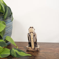 Decorative Egyptian hippo goddess on a wooden door with green leaves in the foreground.