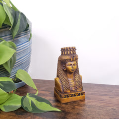 Decorative Egyptian Queen Mutnejmet Statue on a wooden surface with plants in the foreground