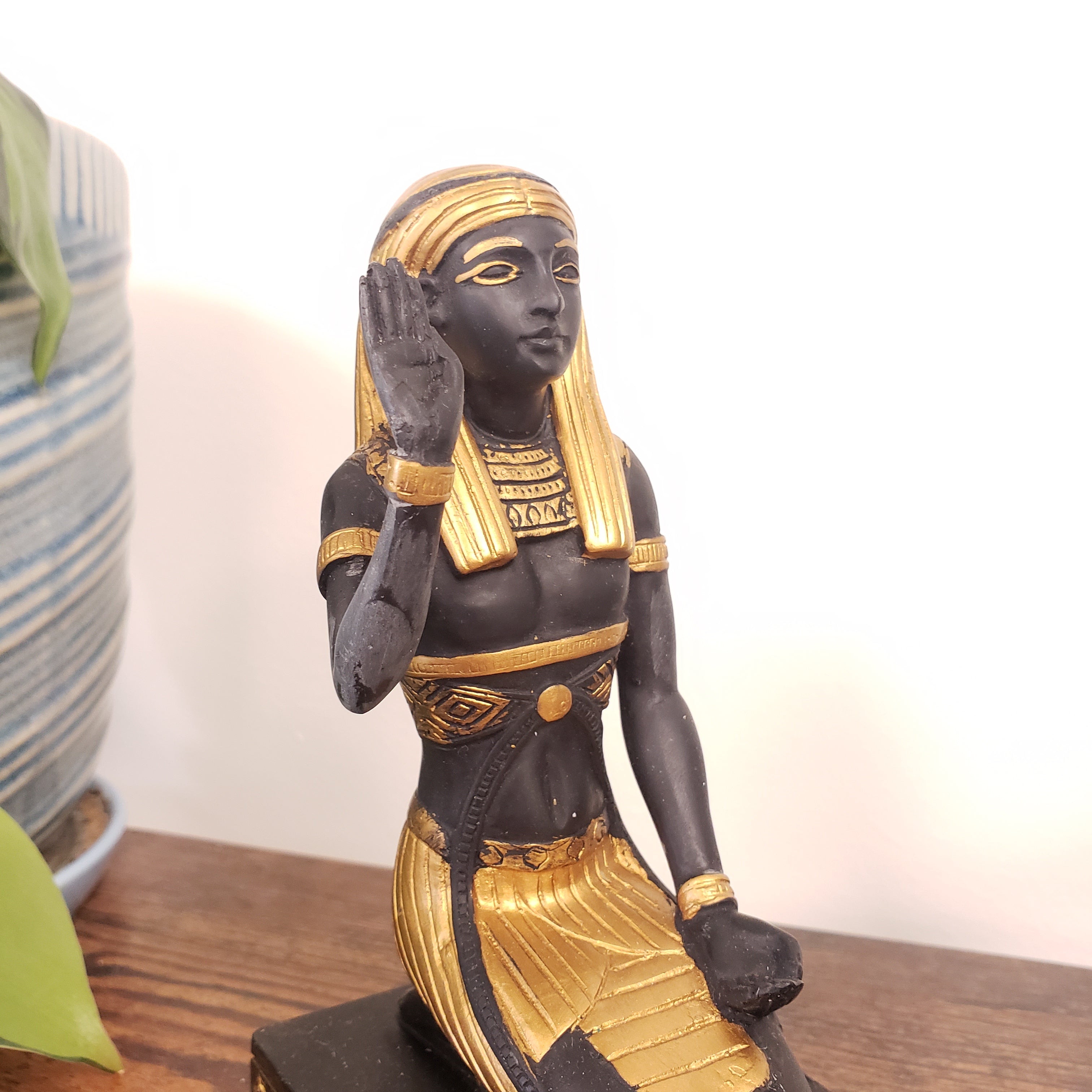 Decorative Egyptian statue figurine of a person in gold and black attire on a white background