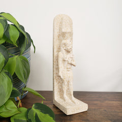 Decorative stone shelf with a natural finish on a wall next to green plants.
