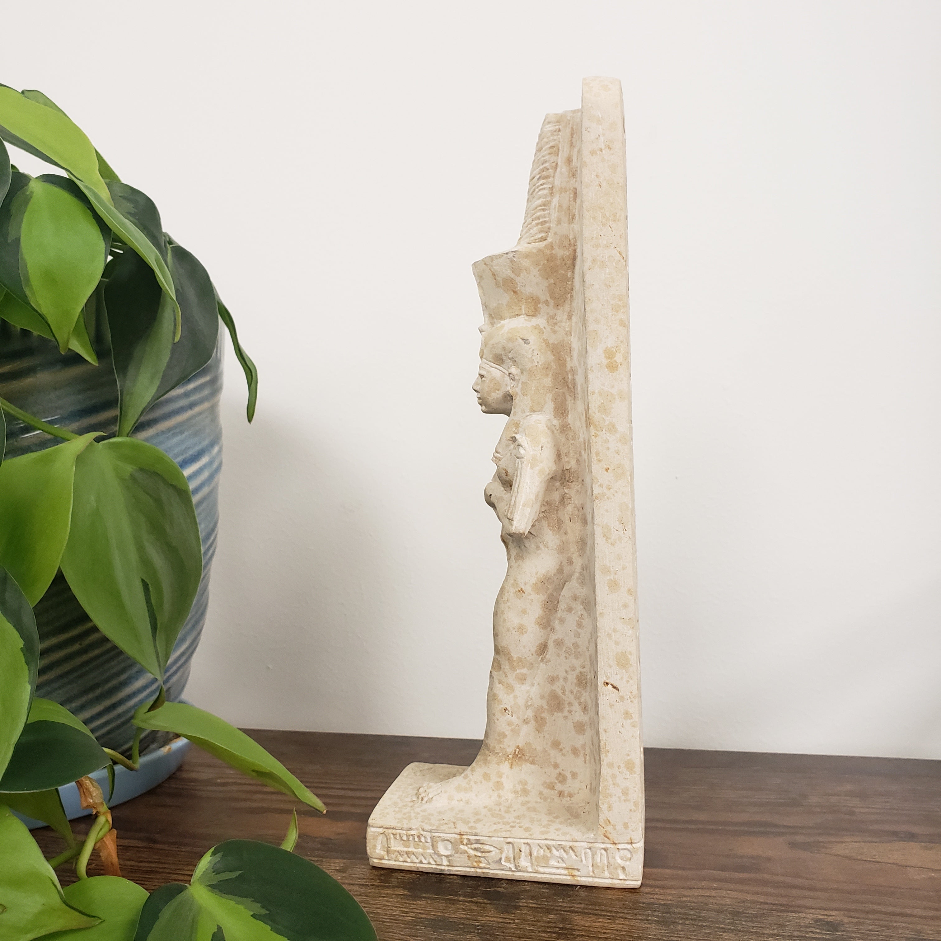 Decorative stone statue of Tiye with plants in the foreground