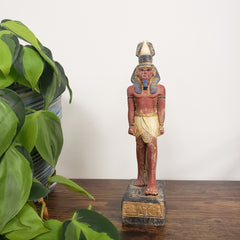 Decorative statue on a wooden base with green leaves in the foreground