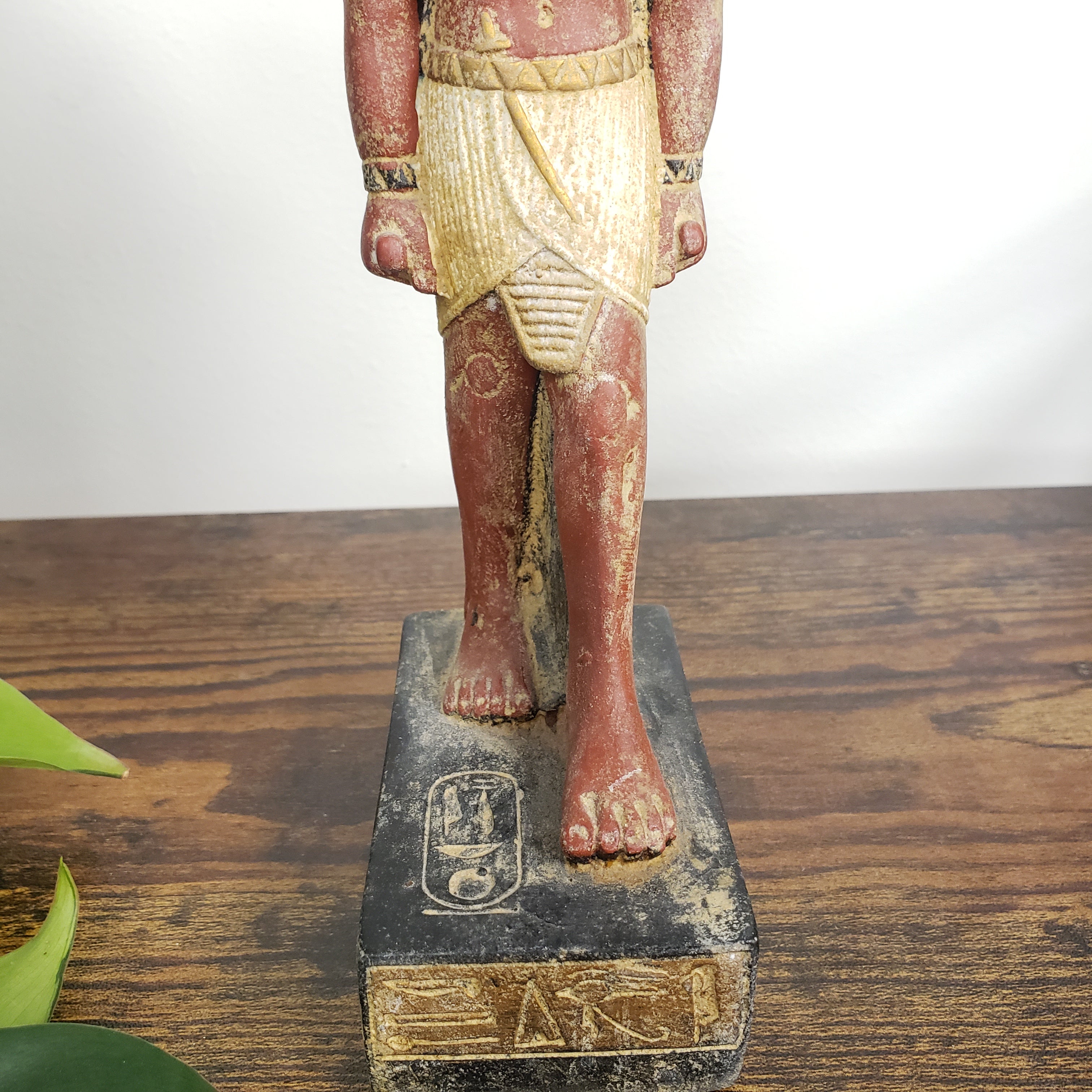 Egyptian Ramses statue with red and gold paint on a wooden surface