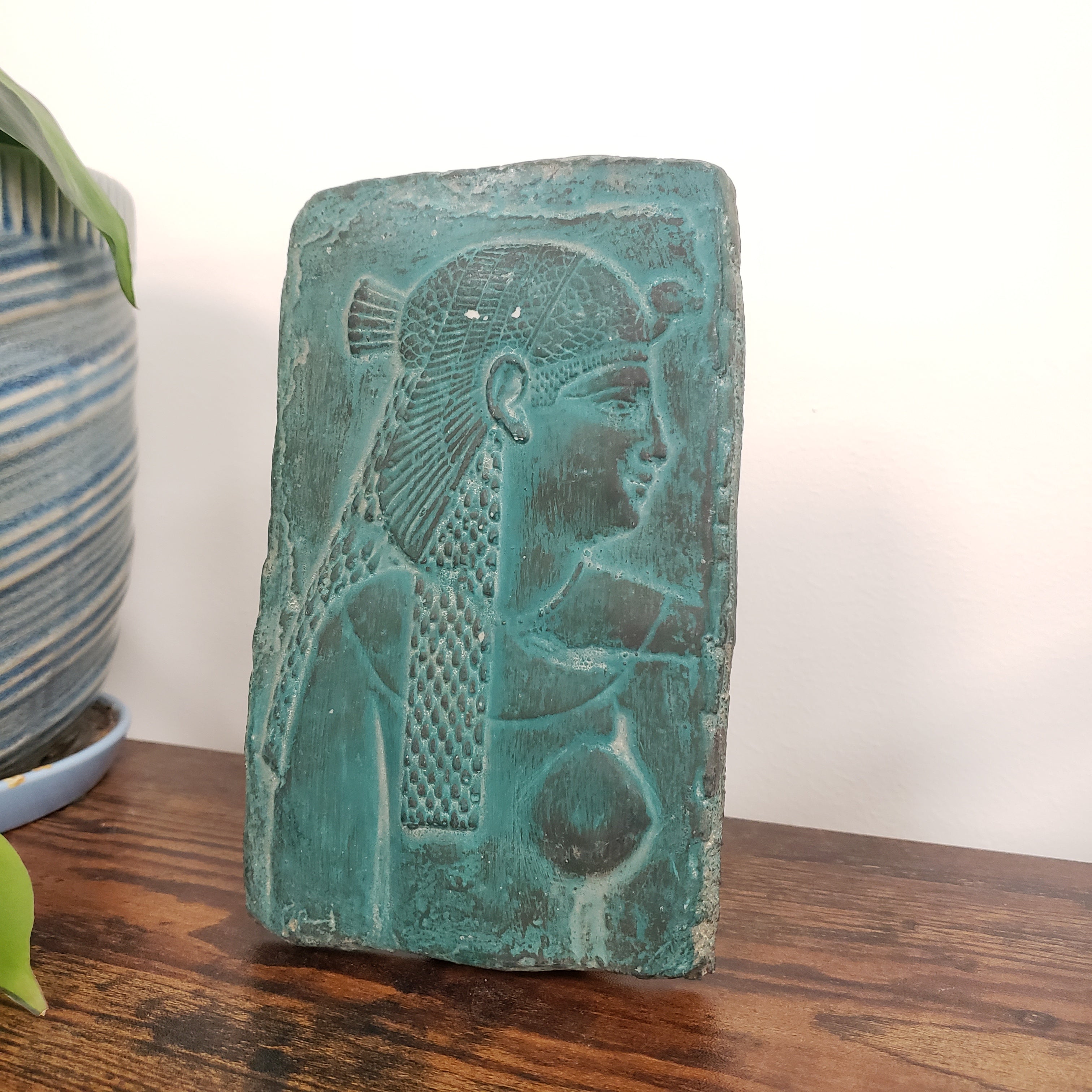 Decorative Cleopatra wall hanging on a white surface and wooden background