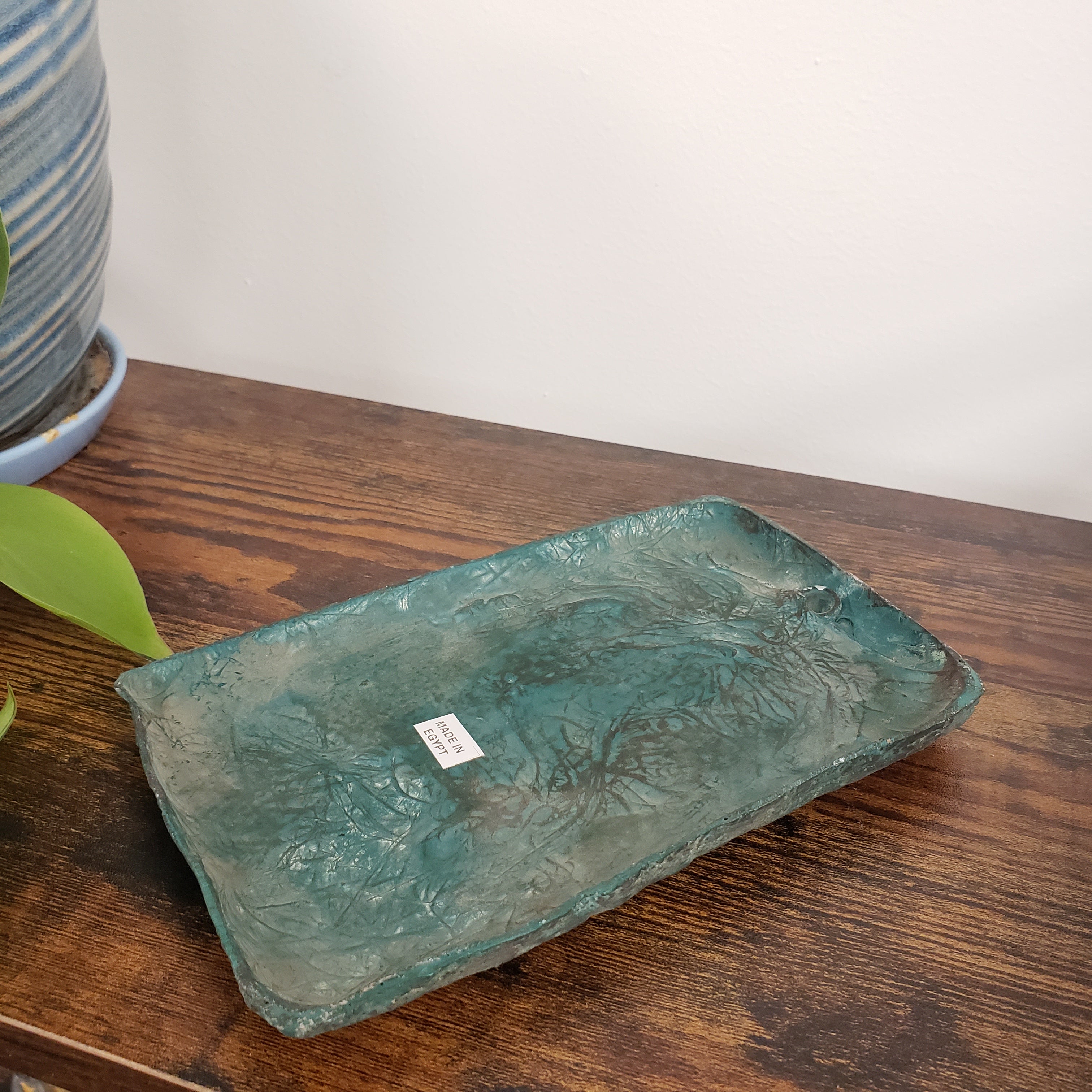 Textured green Cleopatra wall hanging on a wooden surface