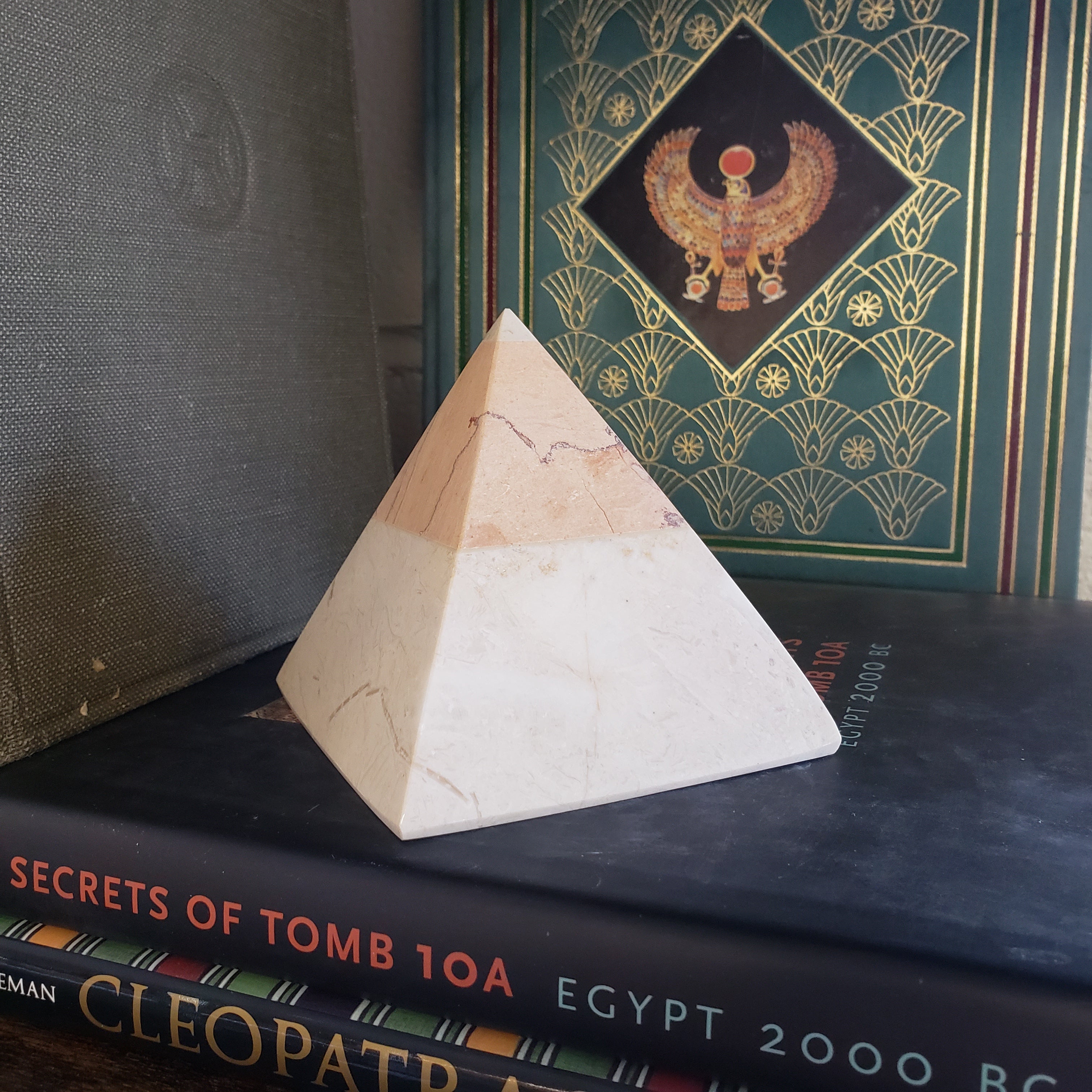 Wooden pyramid model on a surface with books in the background