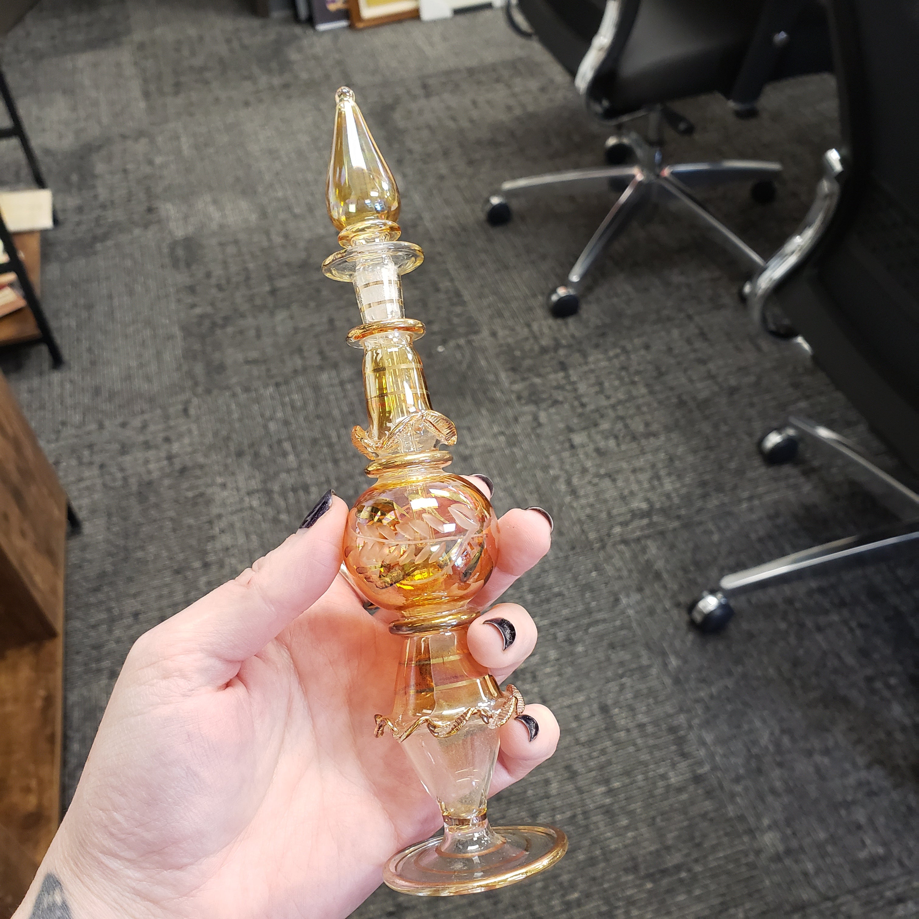 Hand holding a decorative glass object with a blurred office background
