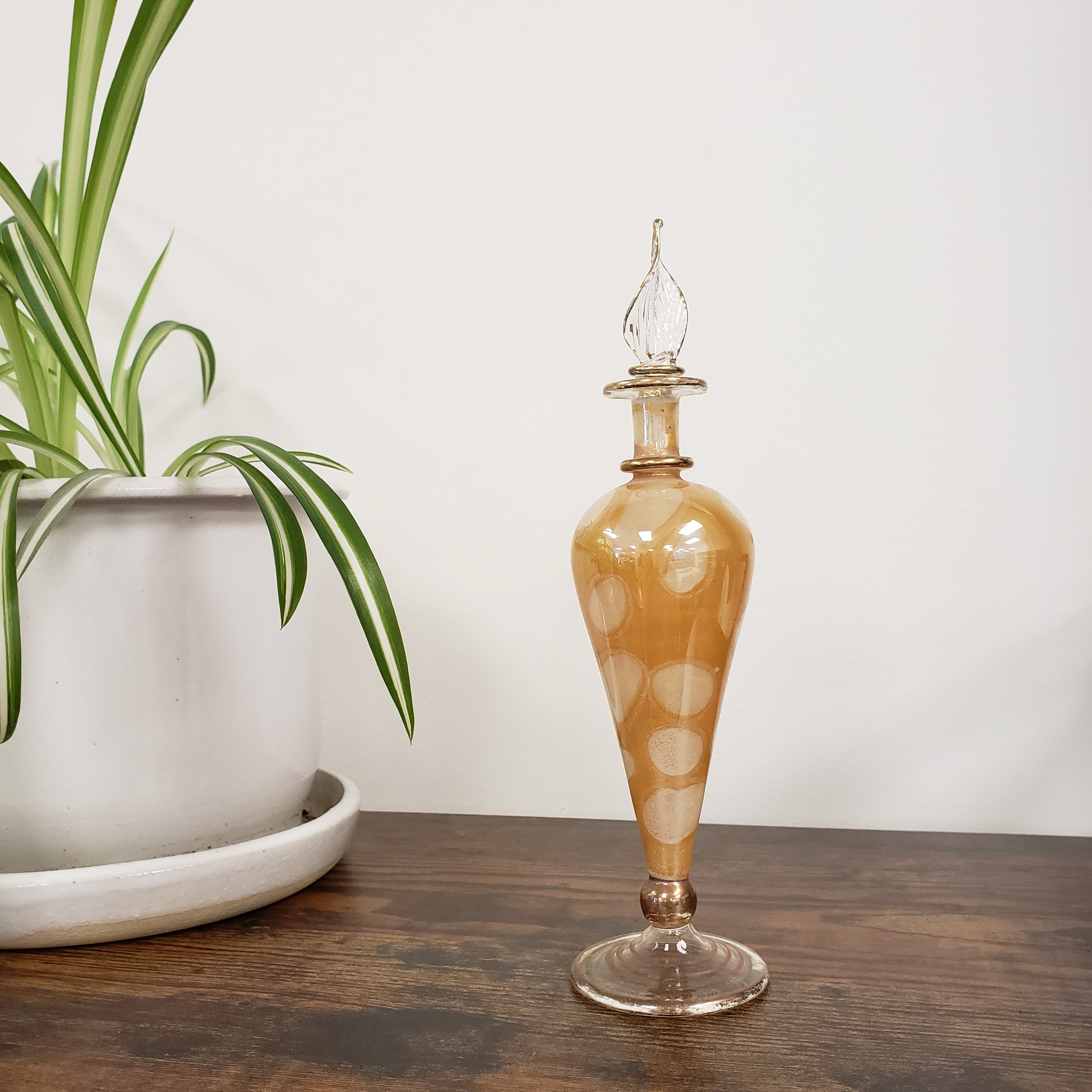 Decorative glass bottle with a polka dot design on a wooden surface.