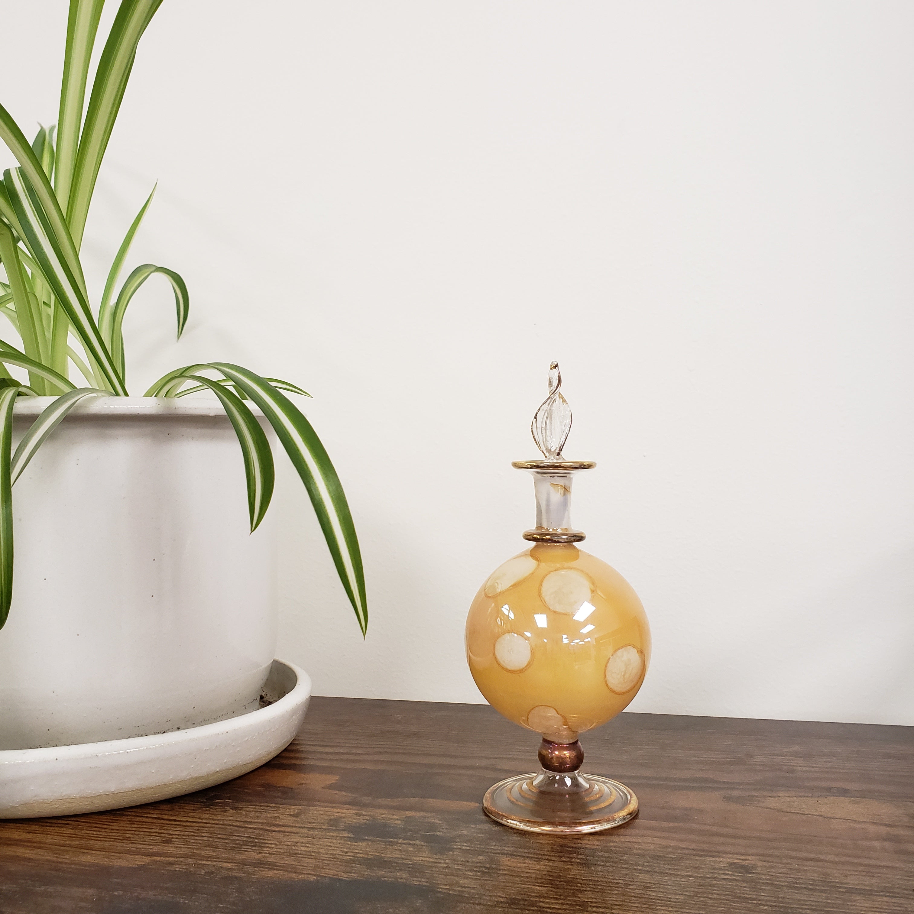 Decorative glass perfume bottle on a wooden surface with a plant in the foreground