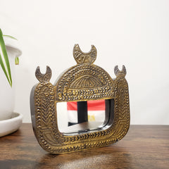 Decorative wall mirror with intricate gold frame on a white wall.