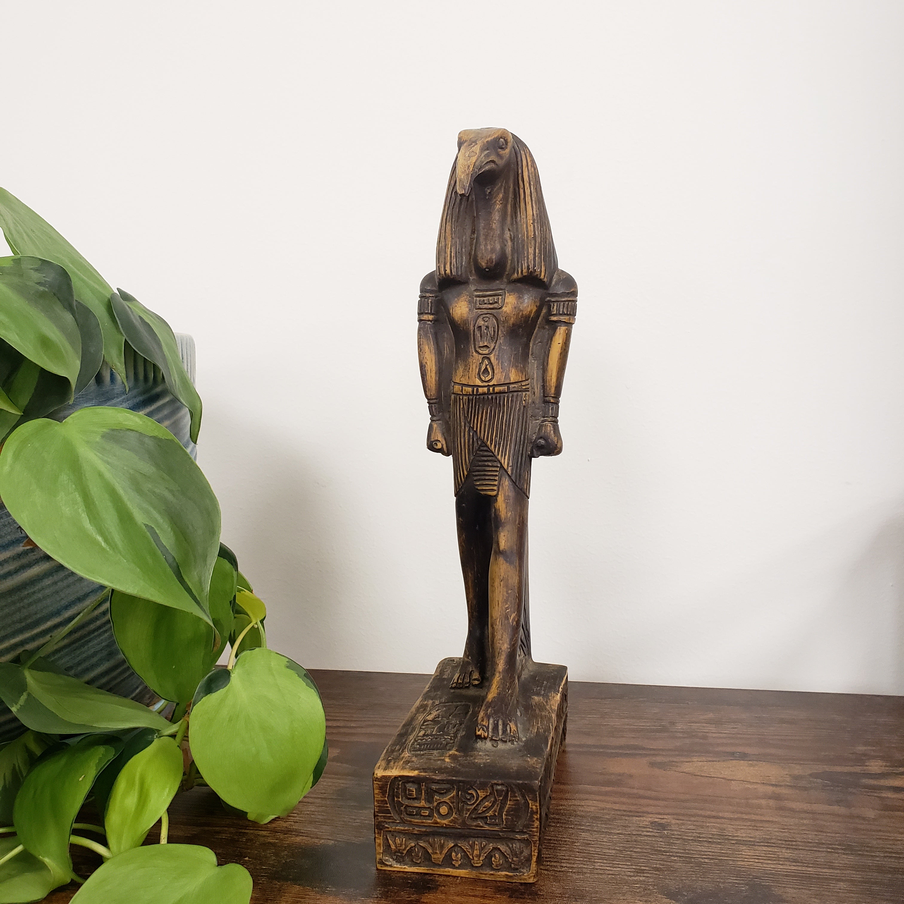 Egyptian god Thoth sculpture on a wooden surface with a plant in the foreground