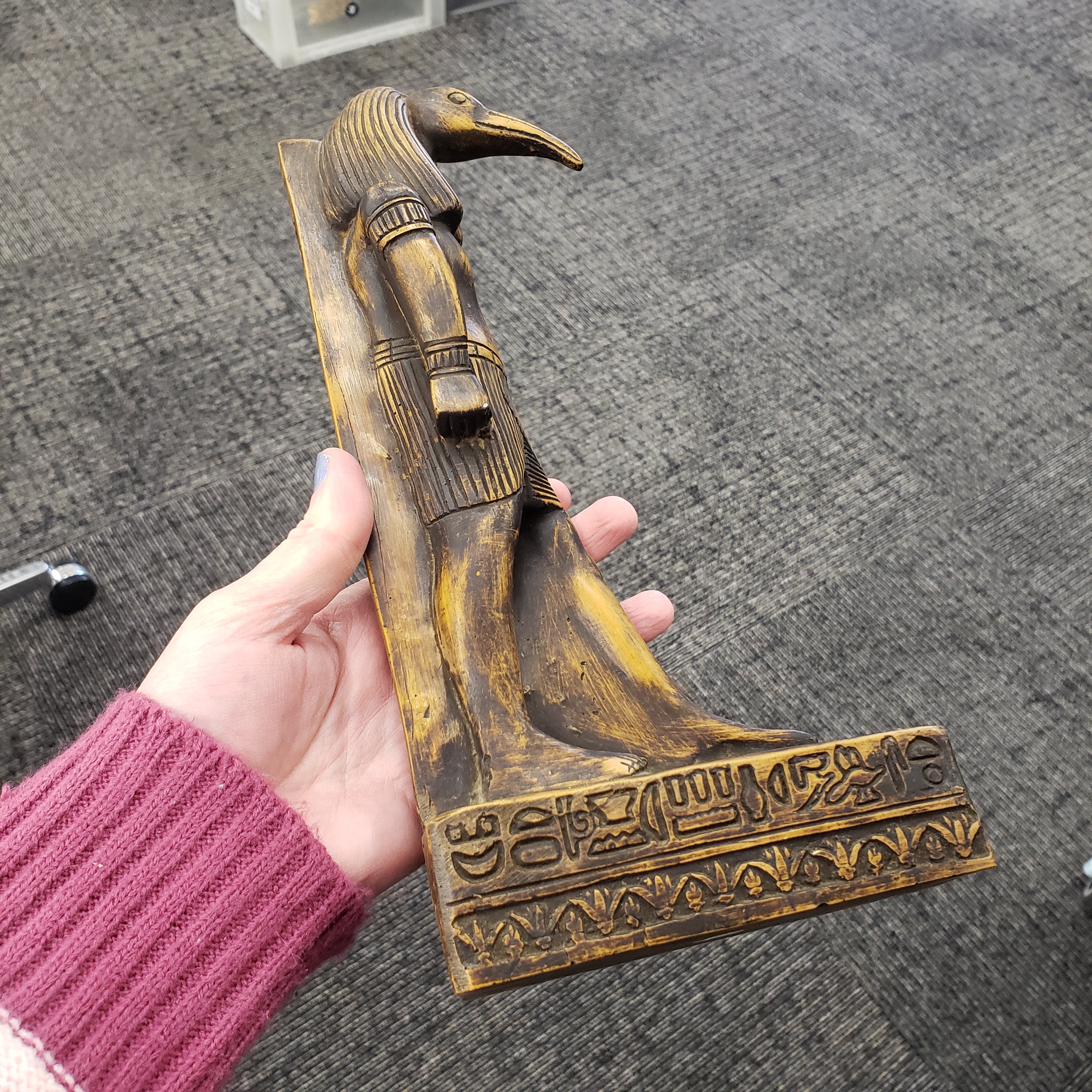 Hand holding a decorative object with intricate designs on a textured surface