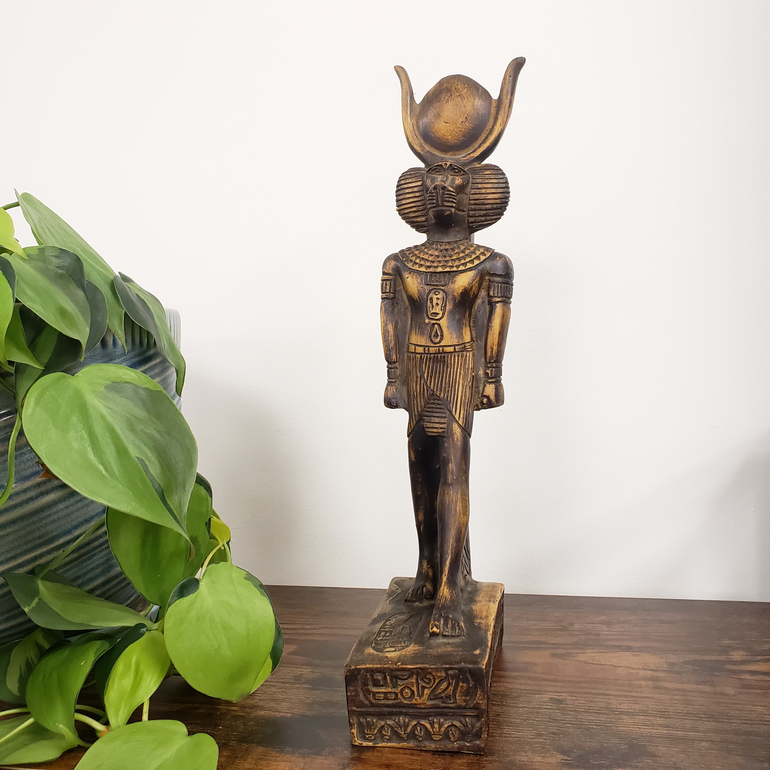 Decorative statue of the Egyptian god Babi  with green leaves in the foreground