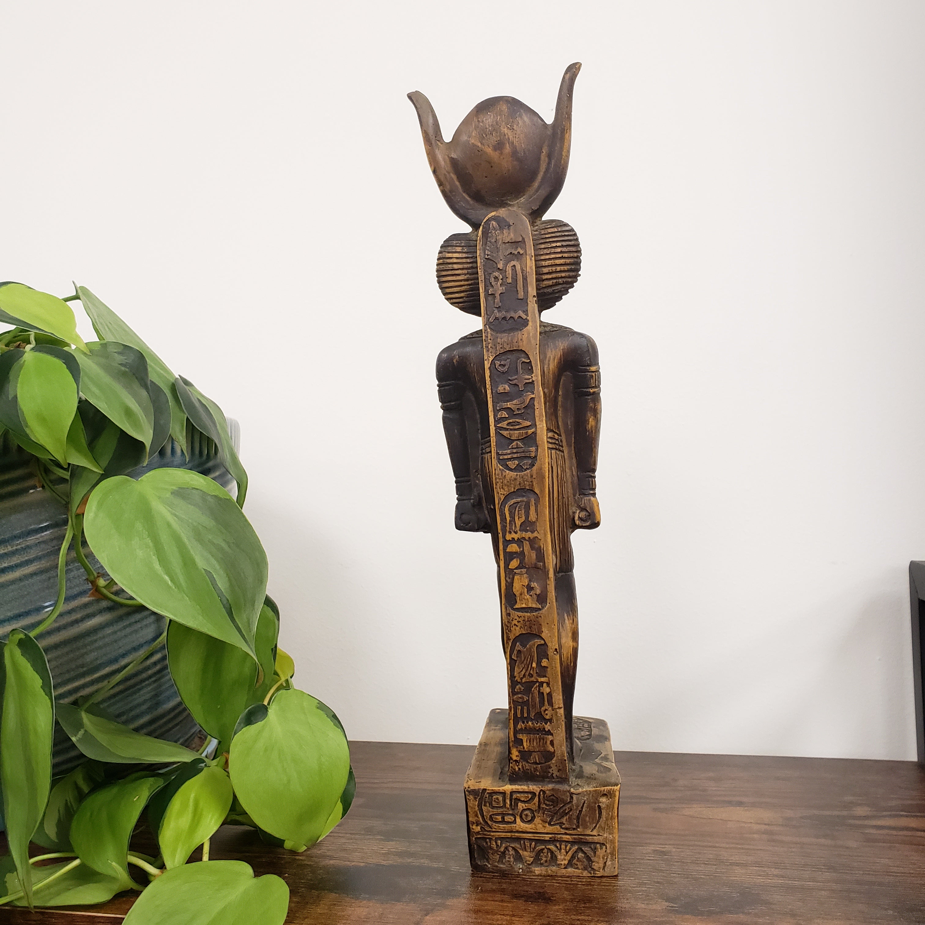 Decorative statue of the Egyptian god Babi  with a plant below on a white background