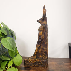 Egyptian god Montu statue with intricate carvings on a white wall.