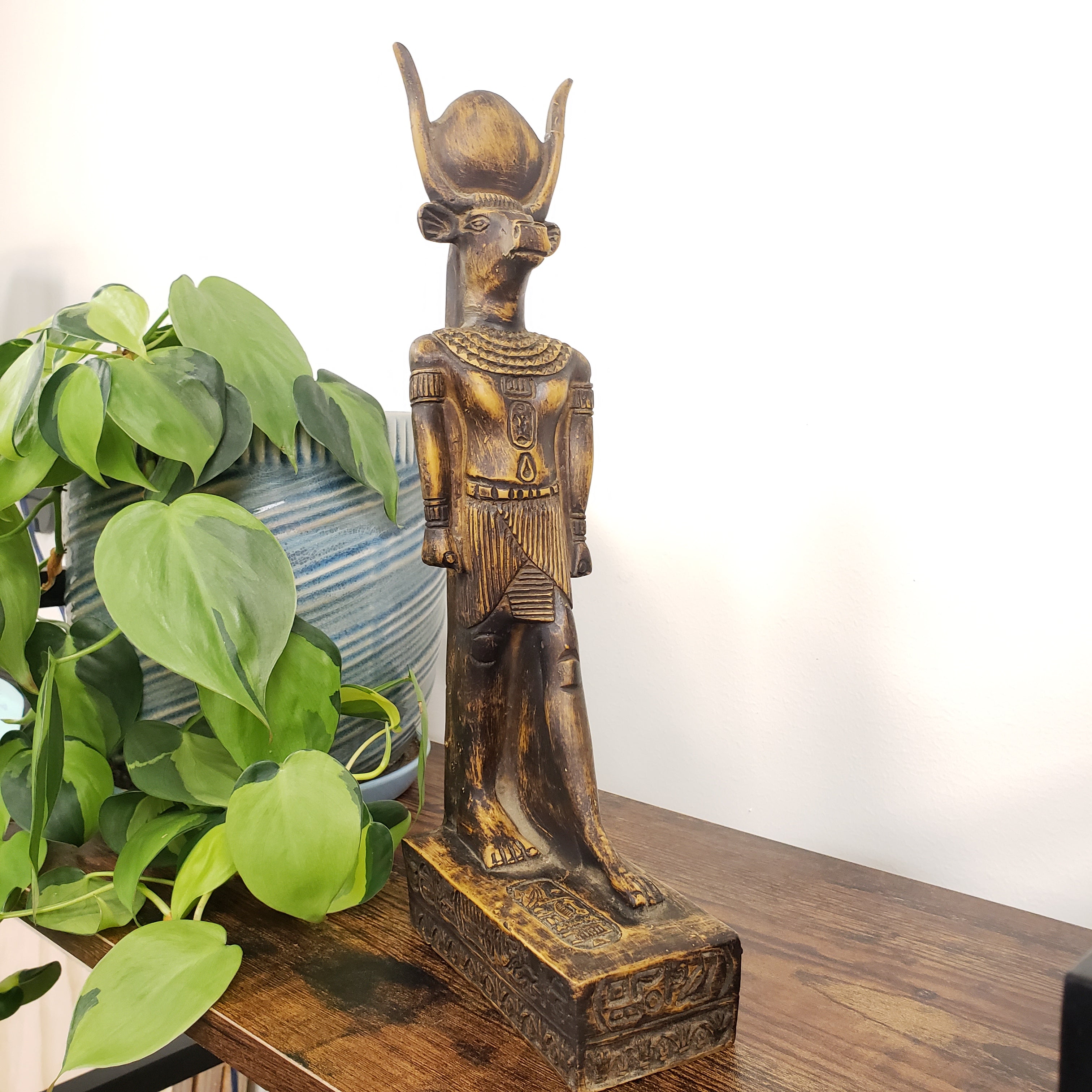 Egyptian god Montu statue with green leaves in the foreground