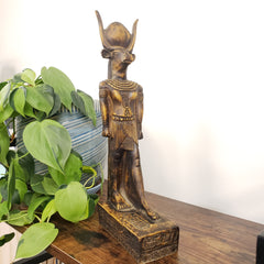 Egyptian god Montu statue with green leaves in the foreground