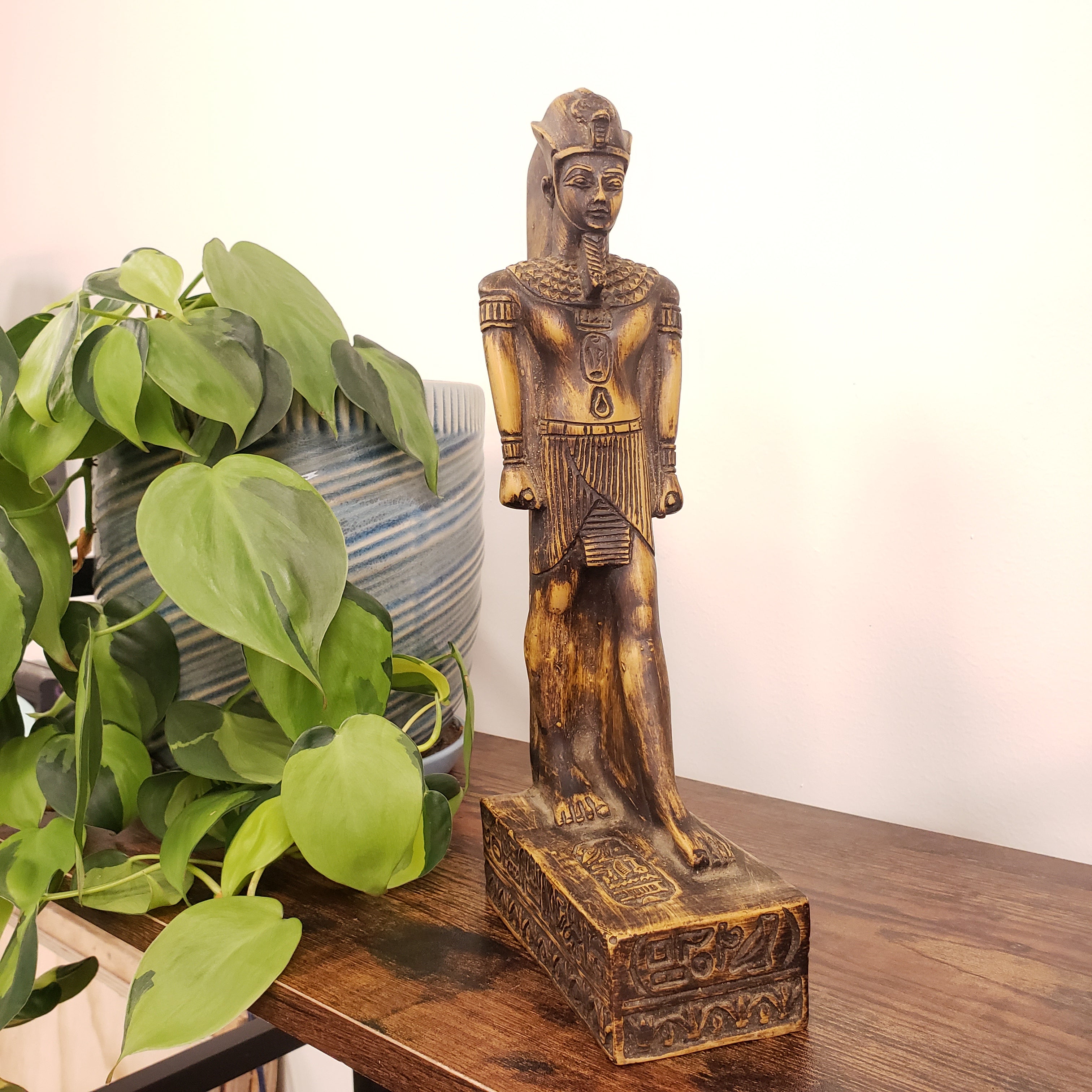 Decorative King Amunhotep Statue with hieroglyphics on a shelf with plants