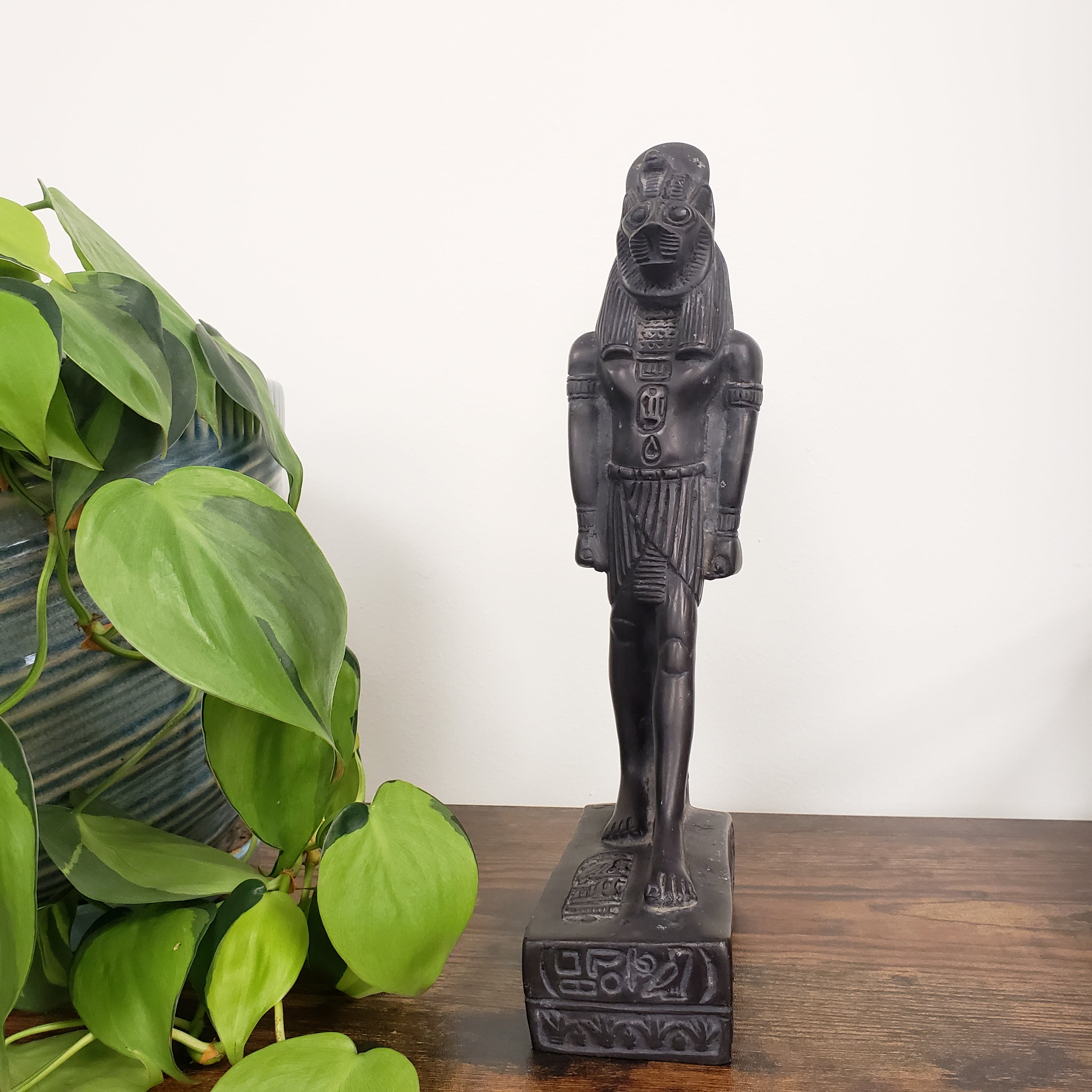 Decorative statue on a wooden shelf with green plants below