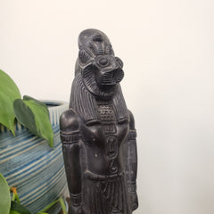 Black stone statue of a figure with hieroglyphics on a white background