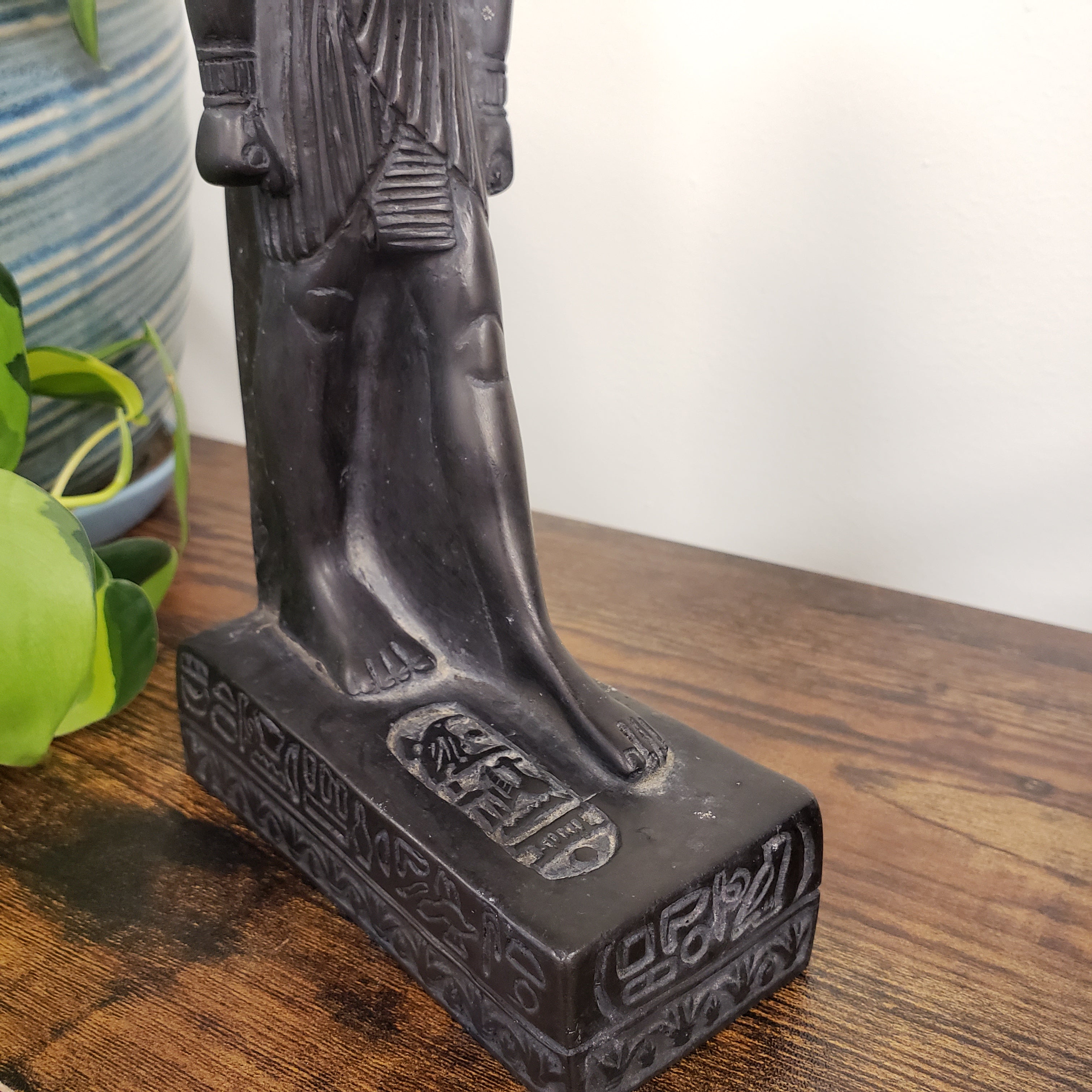 Black black Egyptian goddess Sekhmet statue with engraved text on a wooden surface