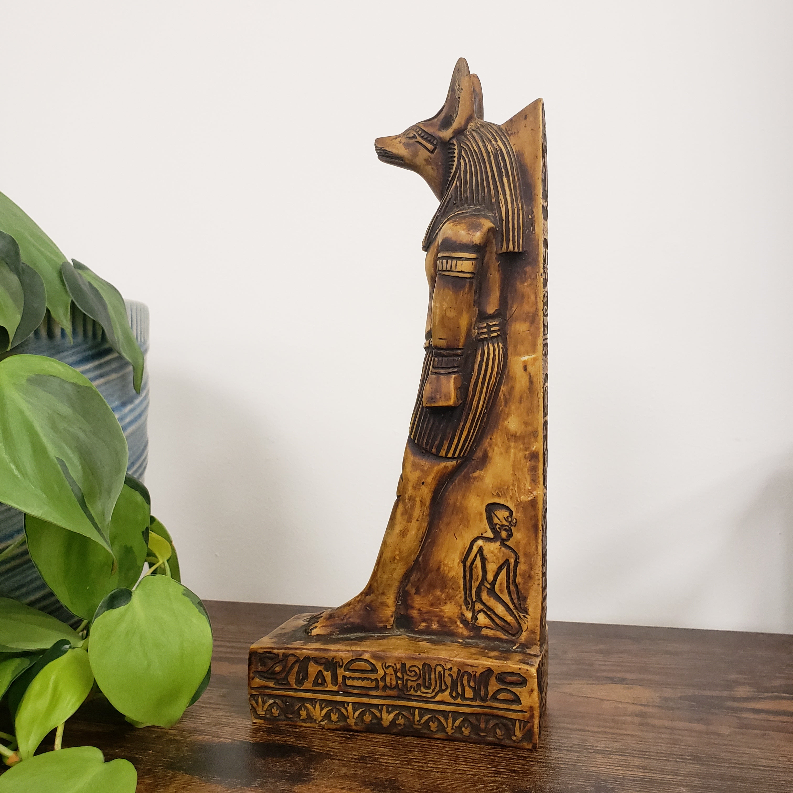 Decorative statue of the Egyptian god Anubis with intricate carvings on a white wall.