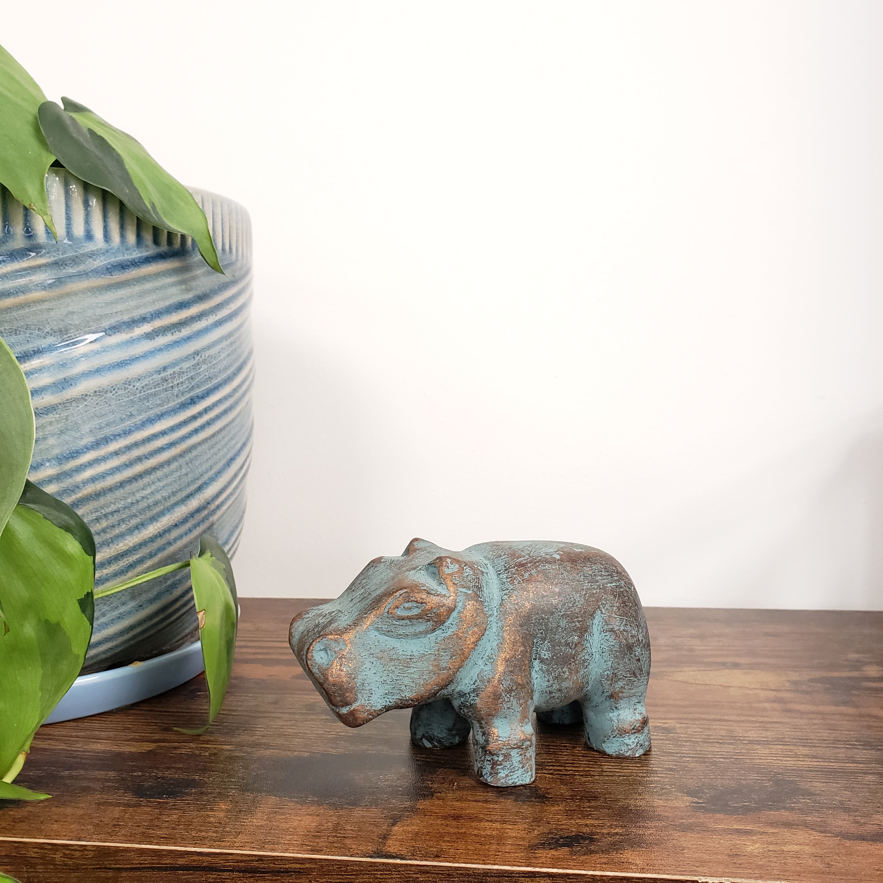 Decorative hippo statue on a wooden door with plants in the foreground.
