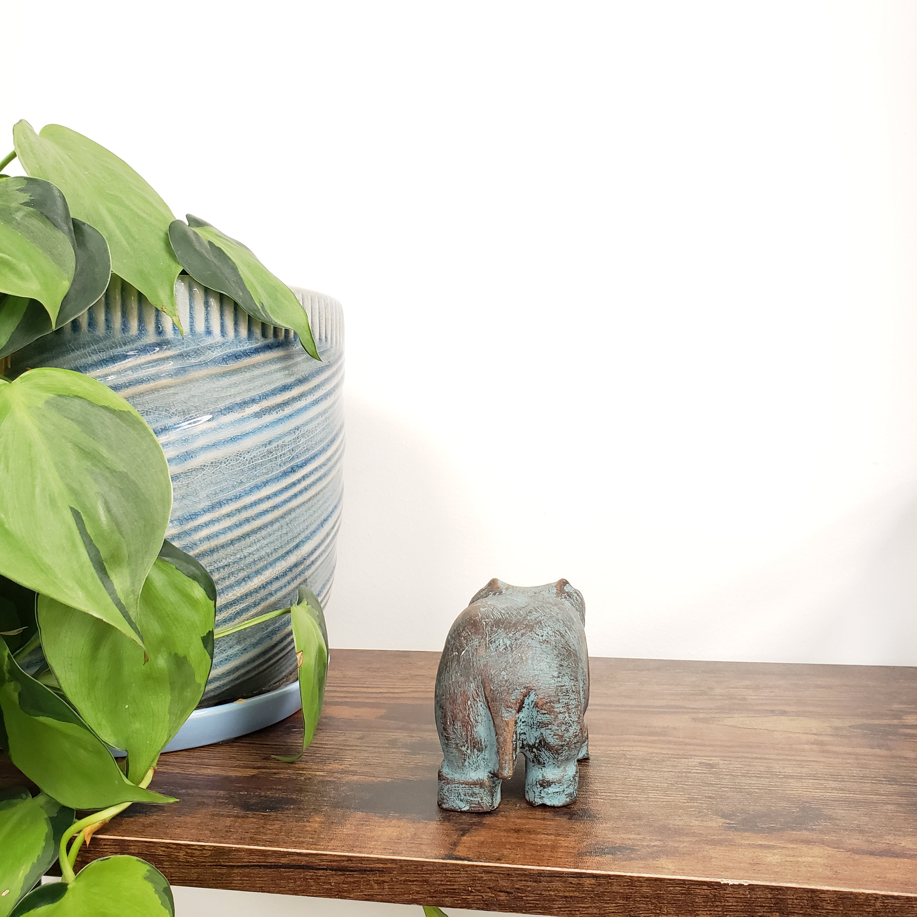 Decorative hippo statue surrounded by green plants.