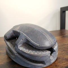 Black sculpture of a scarab with carvings on a wooden surface