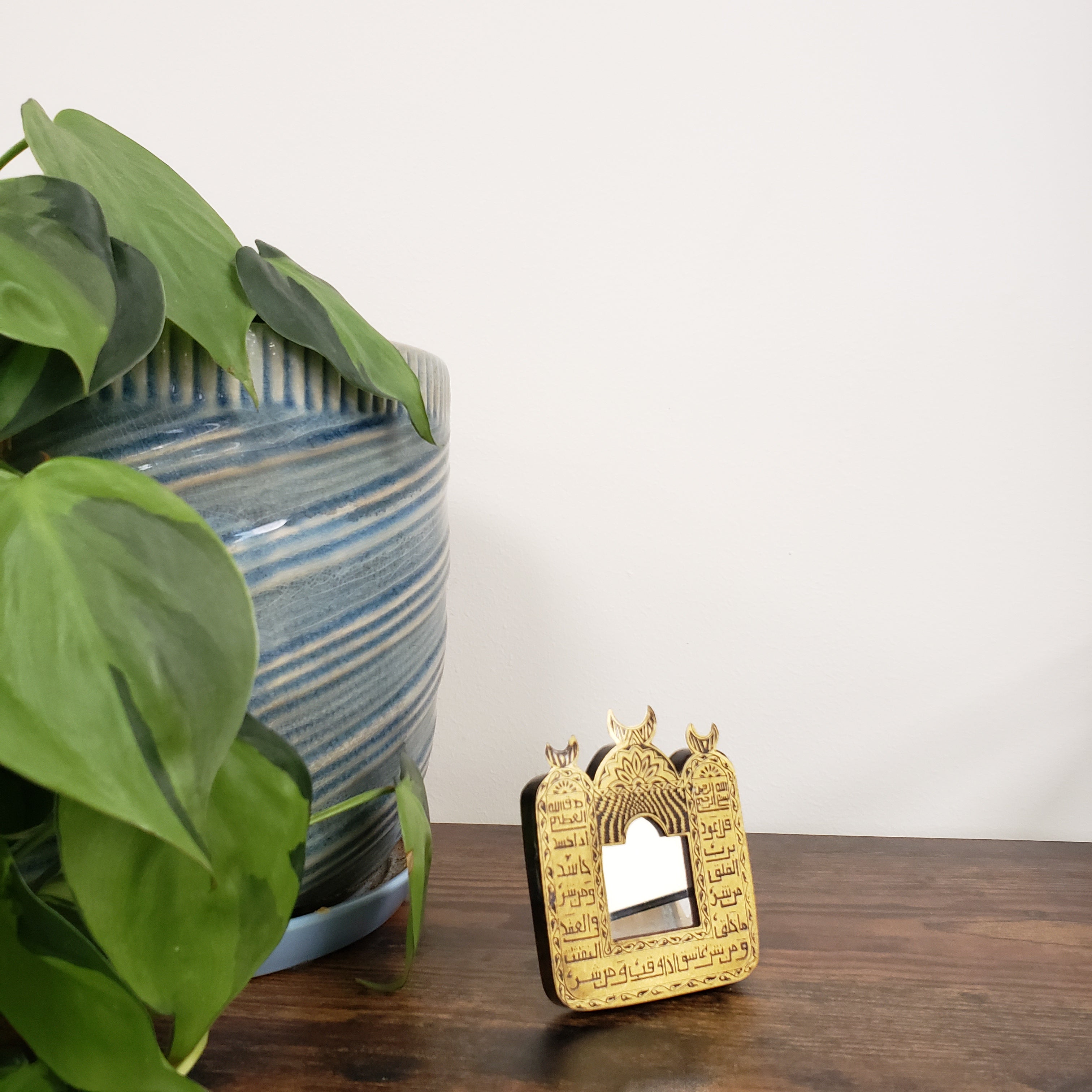 Gold decorative item on a wooden surface with green leaves in the foreground