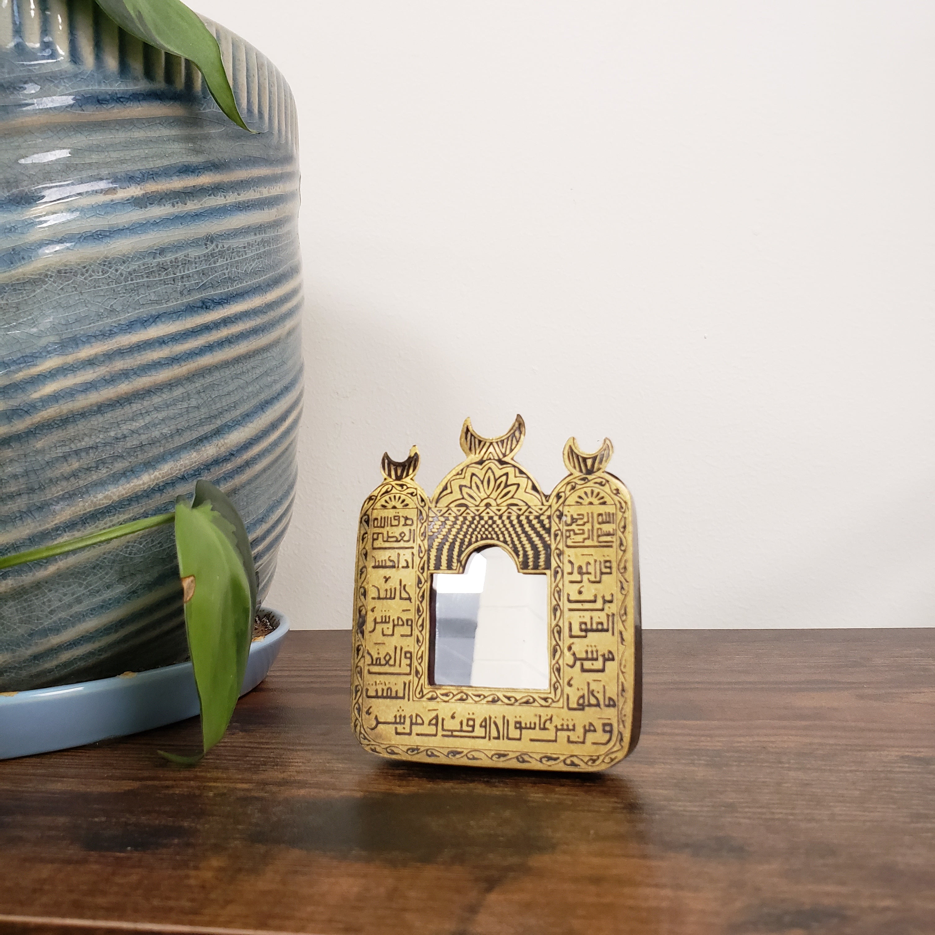 Decorative mirror with Arabic text with intricate designs on a wooden surface.