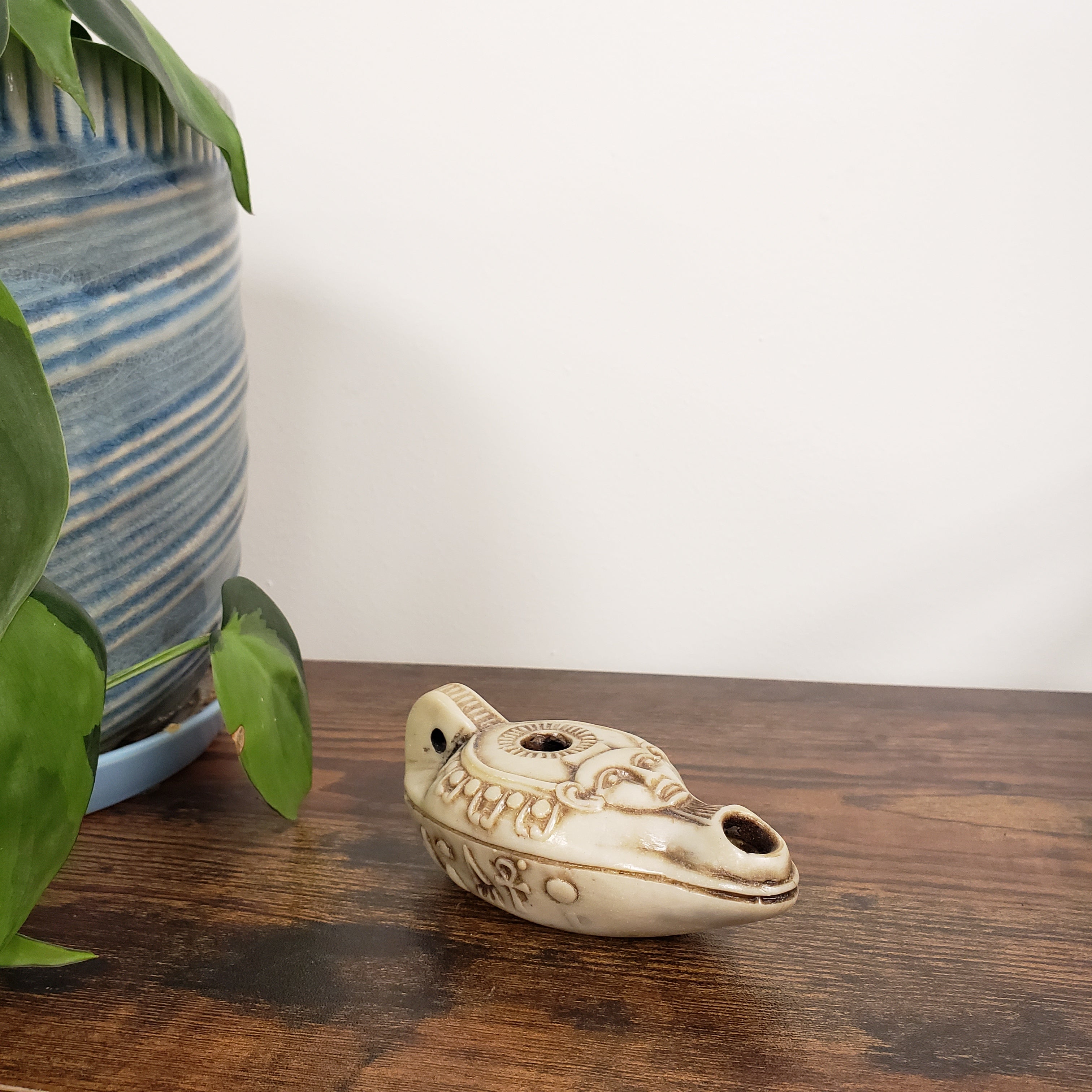 Decorative ceramic Egyptian goddess Hathor Oil Lamp on a wooden surface with plants in the foreground