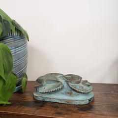 Decorative Egyptian scarab statue on a wooden panel with a plant in the foreground.