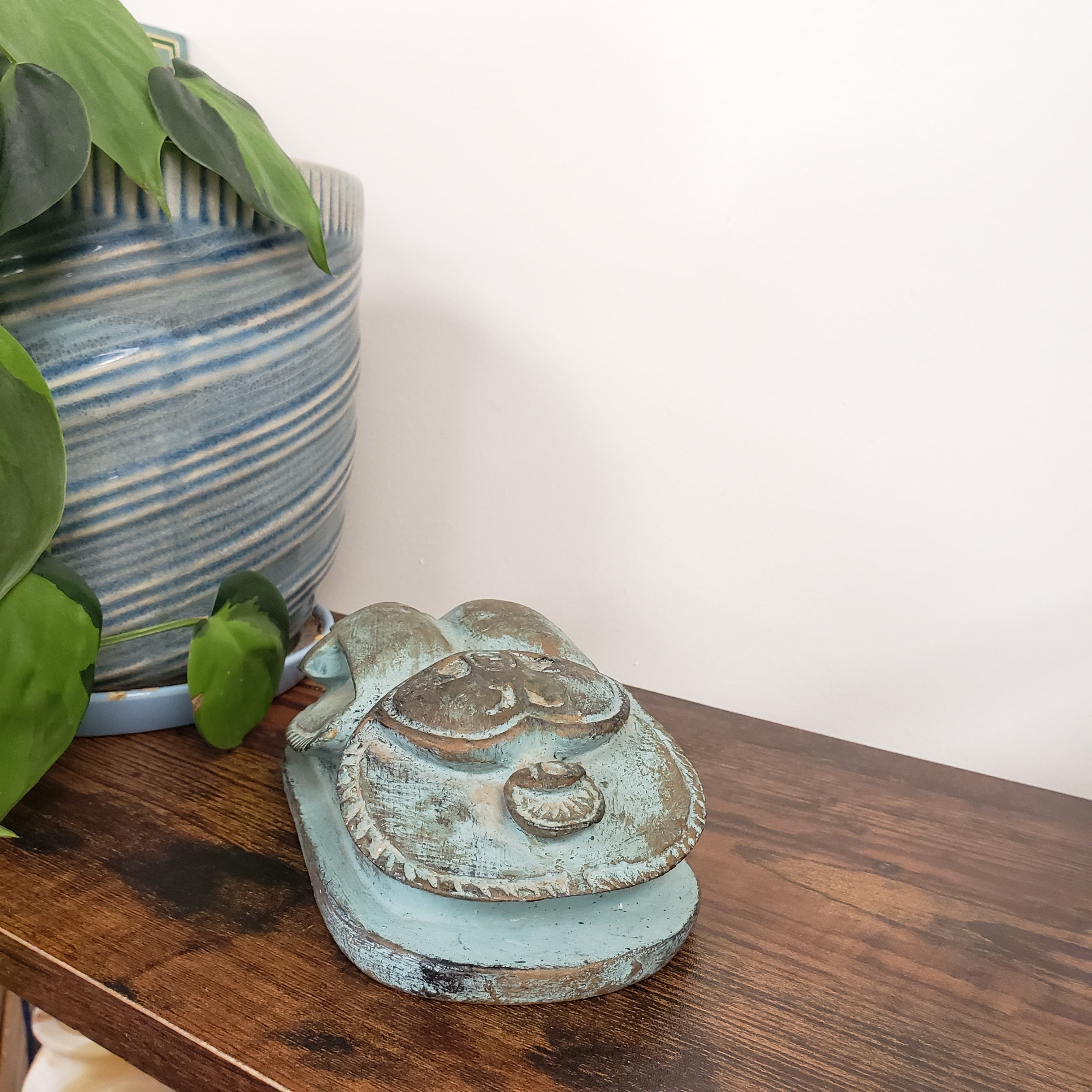 Decorative Egyptian scarab statue with a wooden surface and plant in the foreground