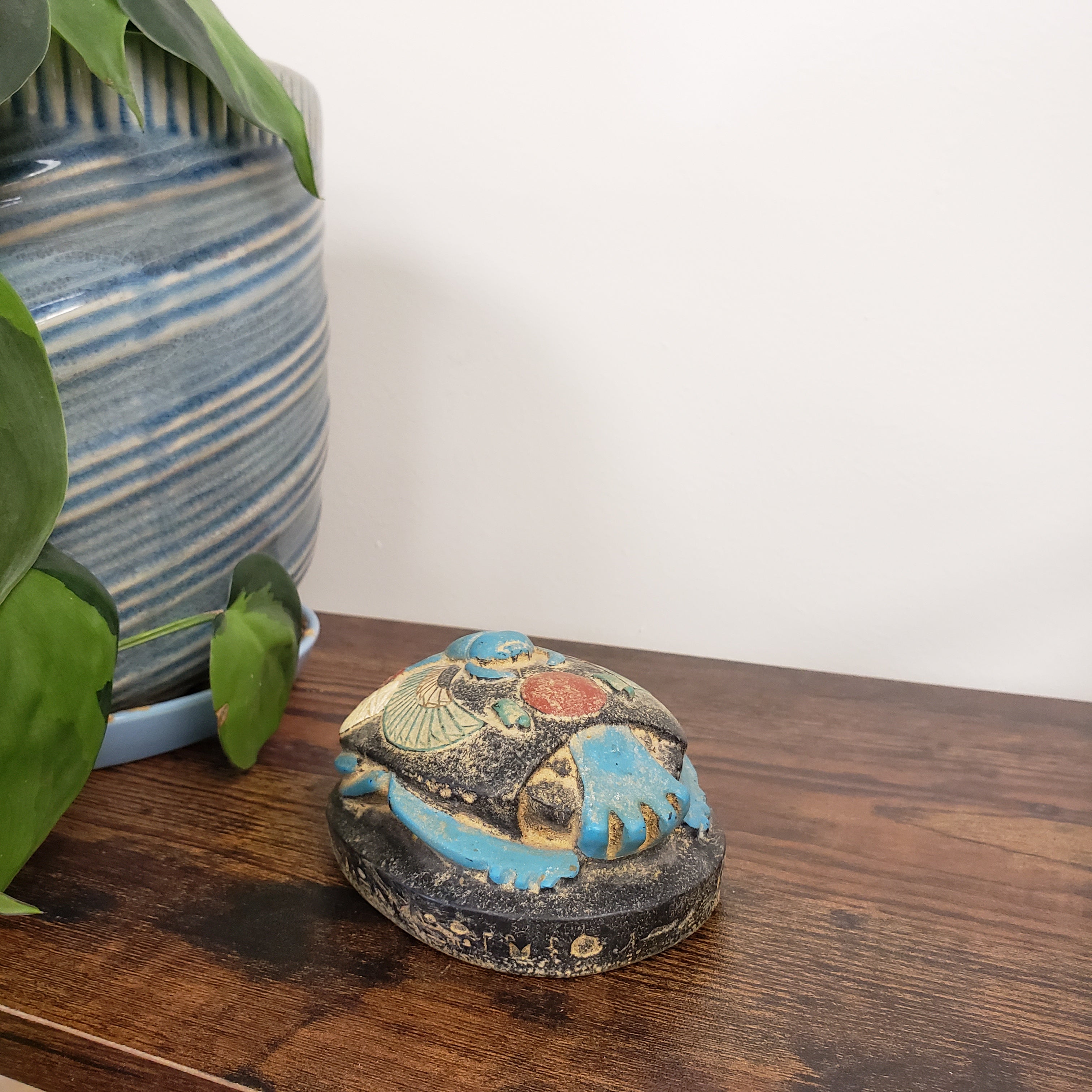 Decorative Egyptian scarab statue with blue and gold design on a wooden surface