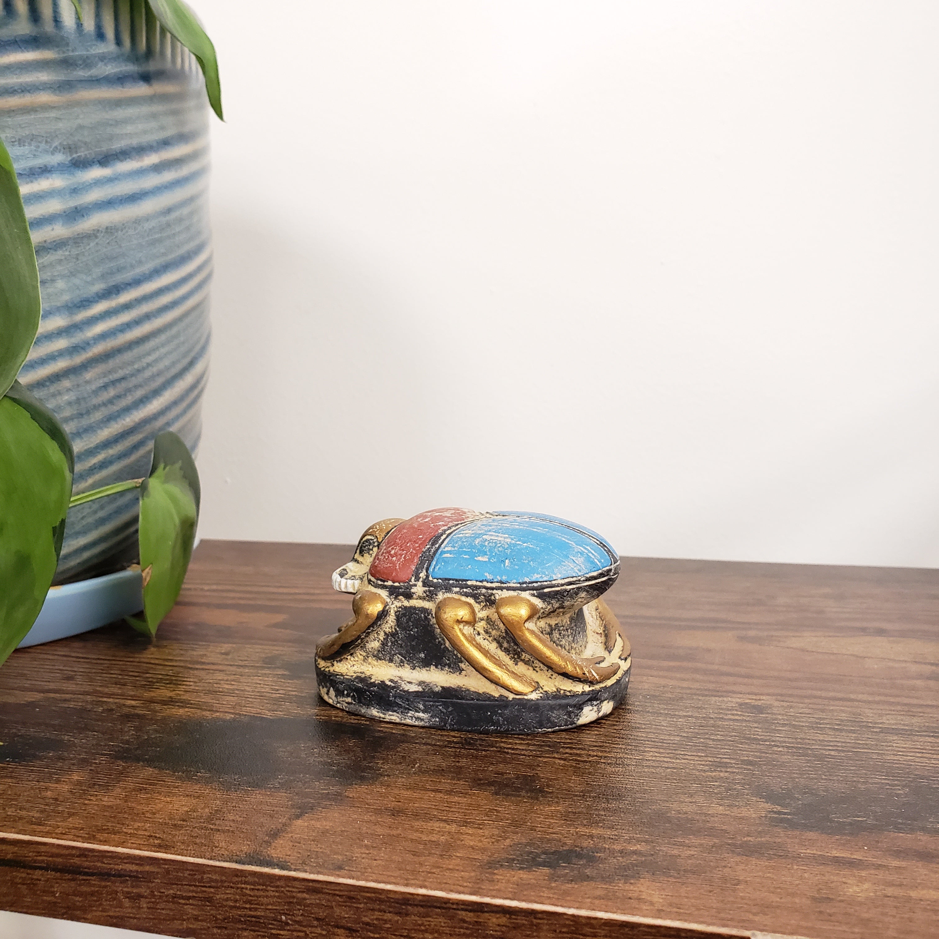 Decorative Egyptian scarab statue with a colorful design on a wooden surface.