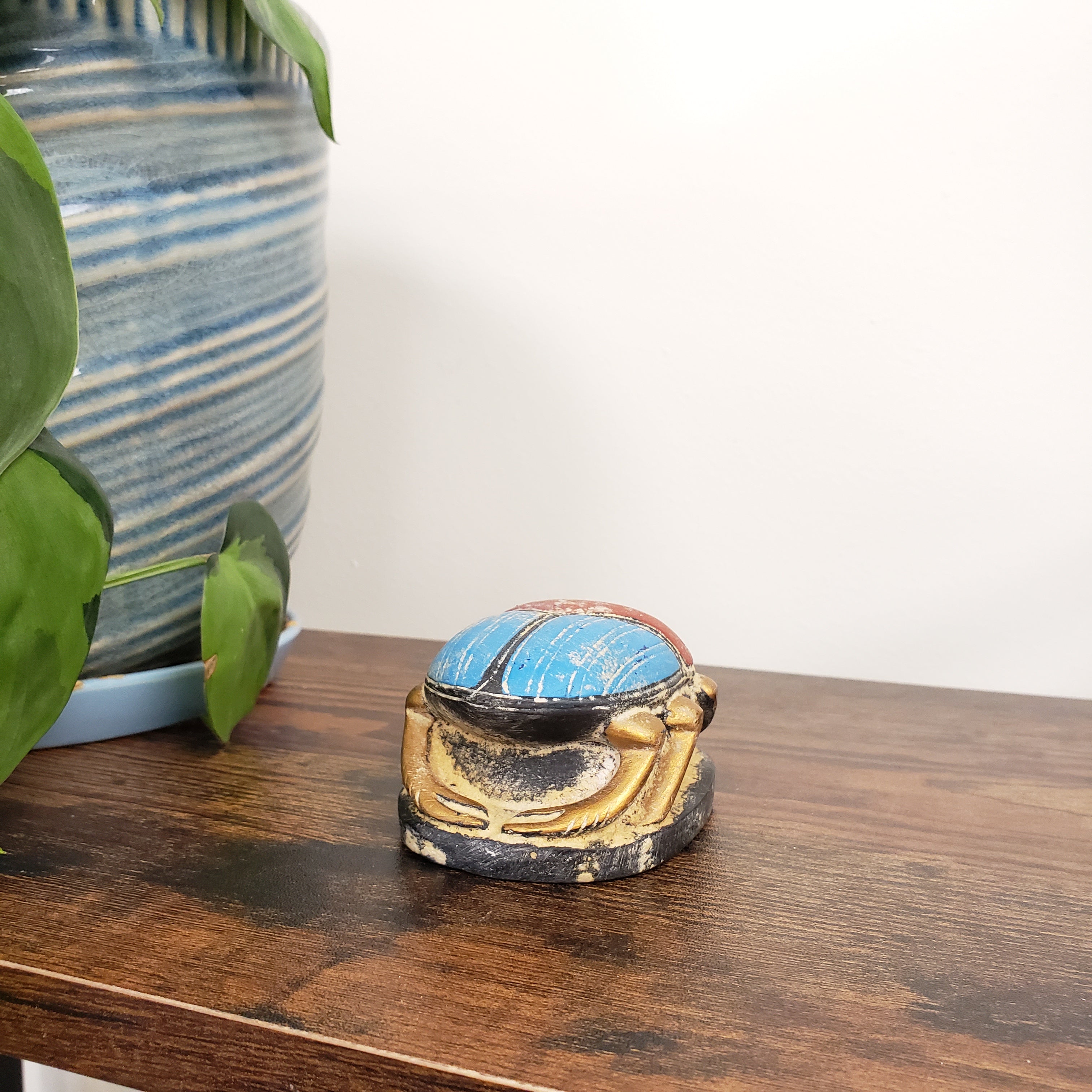 Decorative Egyptian scarab statue with a blue and gold design on a wooden door.