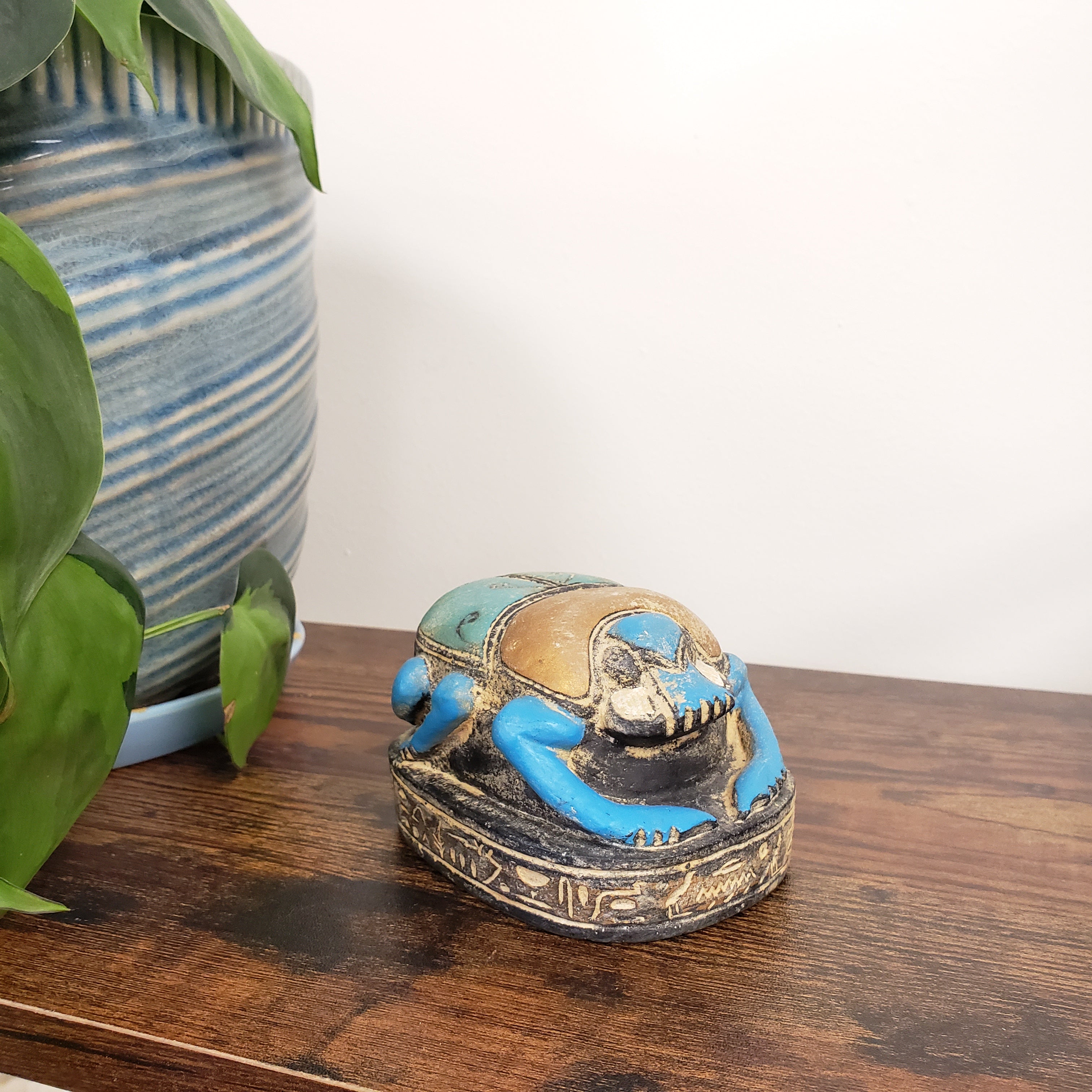 Decorative Egyptian scarab statue with blue and gold design on a wooden door