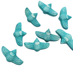 Nine turquoise scarab-shaped beads with carved feather patterns and white inlay details, arranged on a plain white background.